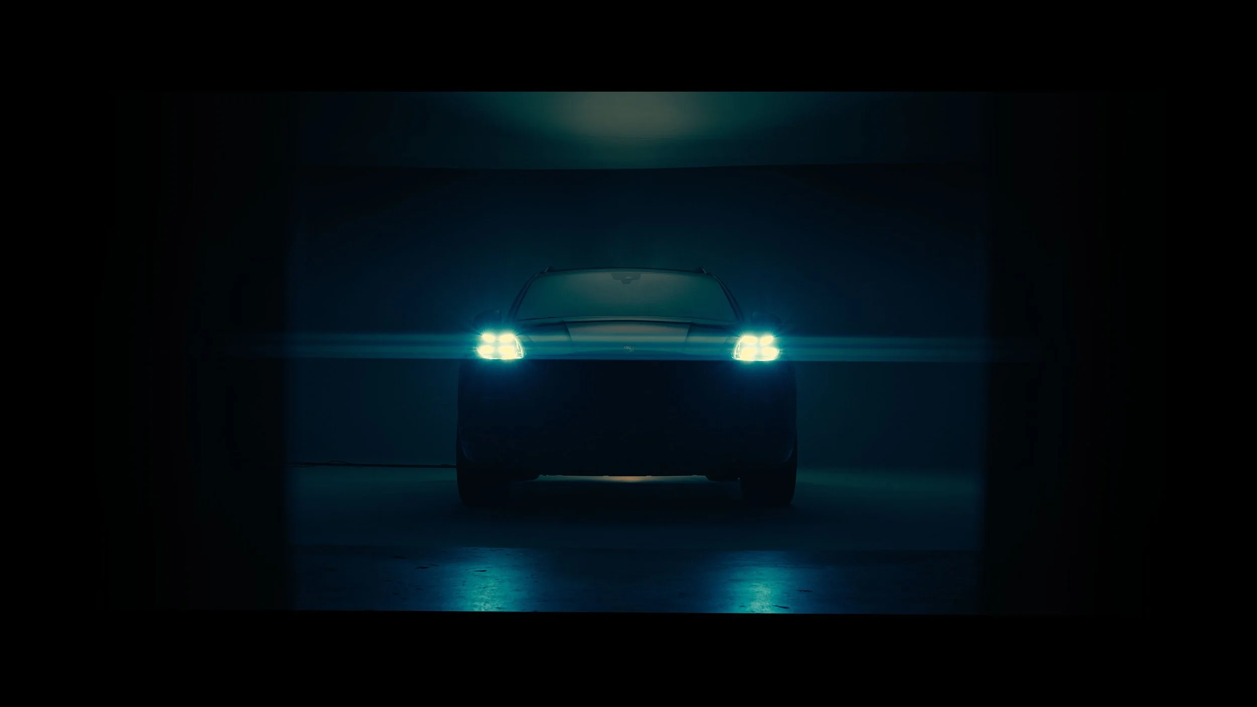 A darkly lit car in a parking garage with bright headlights on.