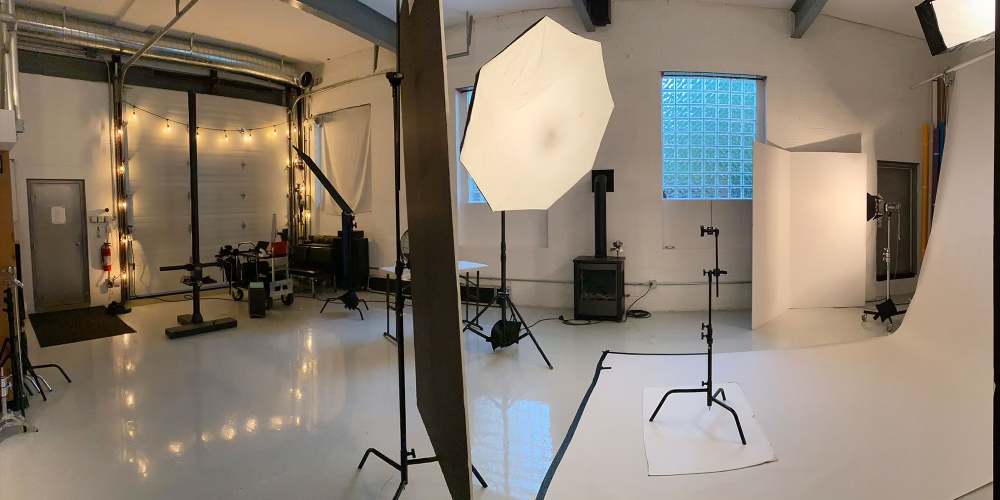 Photography studio with white background, softbox lights, and various photography equipment.Professional photography studio featuring commercial lighting equipment, seamless backgrounds and production facilities for advertising, product and portrait