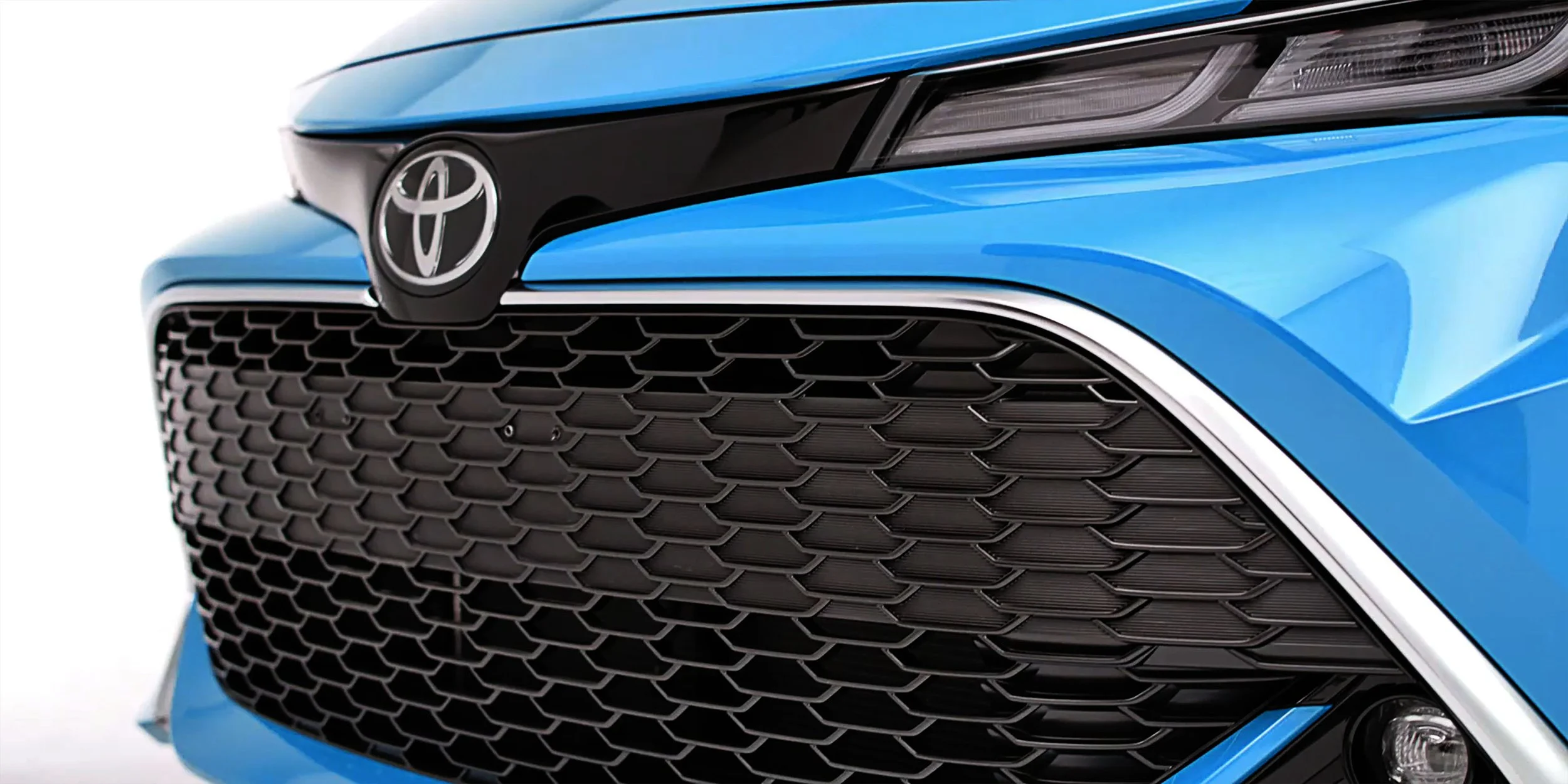 Close-up of the front grille and headlight of a blue Toyota vehicle.