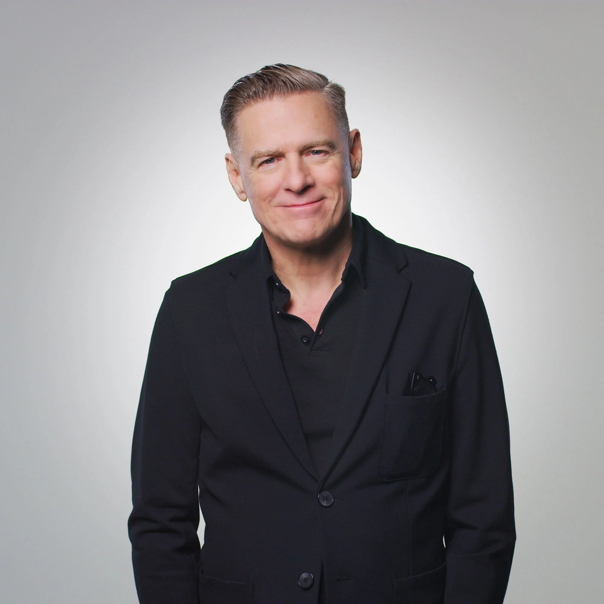 Studio portrait of a man in a black suit against a light grey background