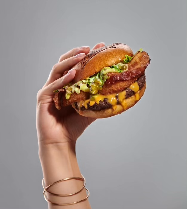 PepsiCo commercial food photography featuring a bacon cheeseburger held in hand