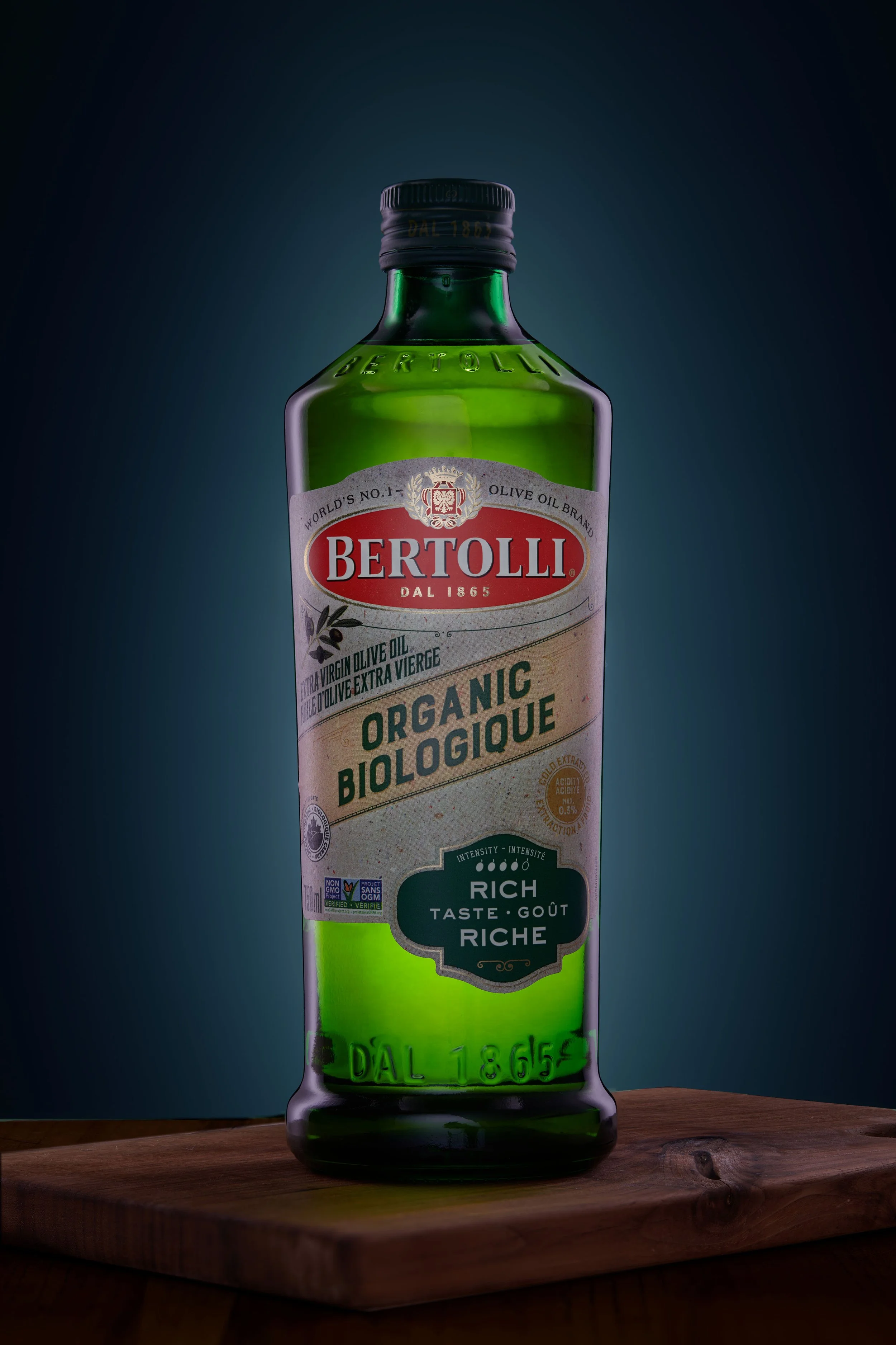 Bottle of Bertolli organic extra virgin olive oil on a wooden surface.