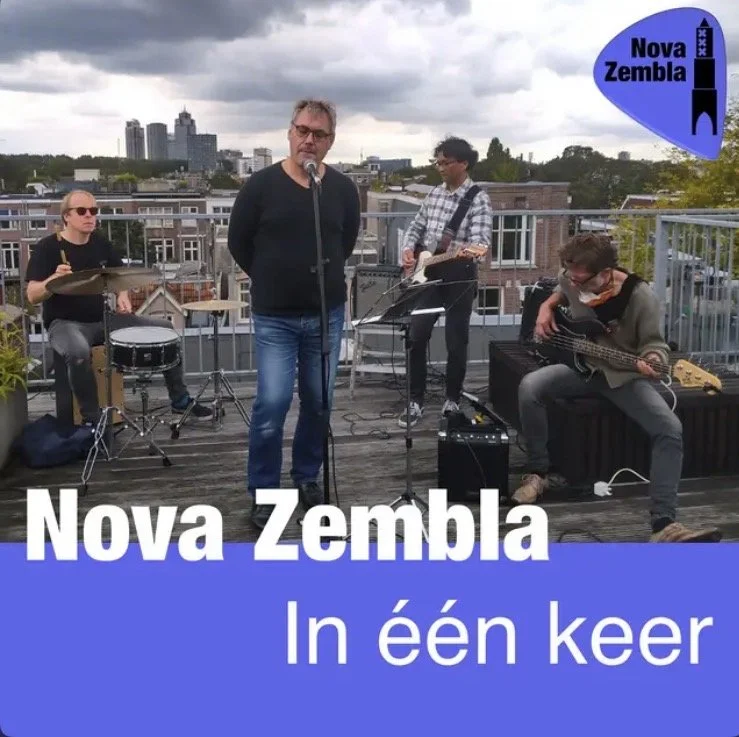 Een band speelt muziek op een dakterras met uitzicht op de stad, met een logo en tekst over Nova Zembla.