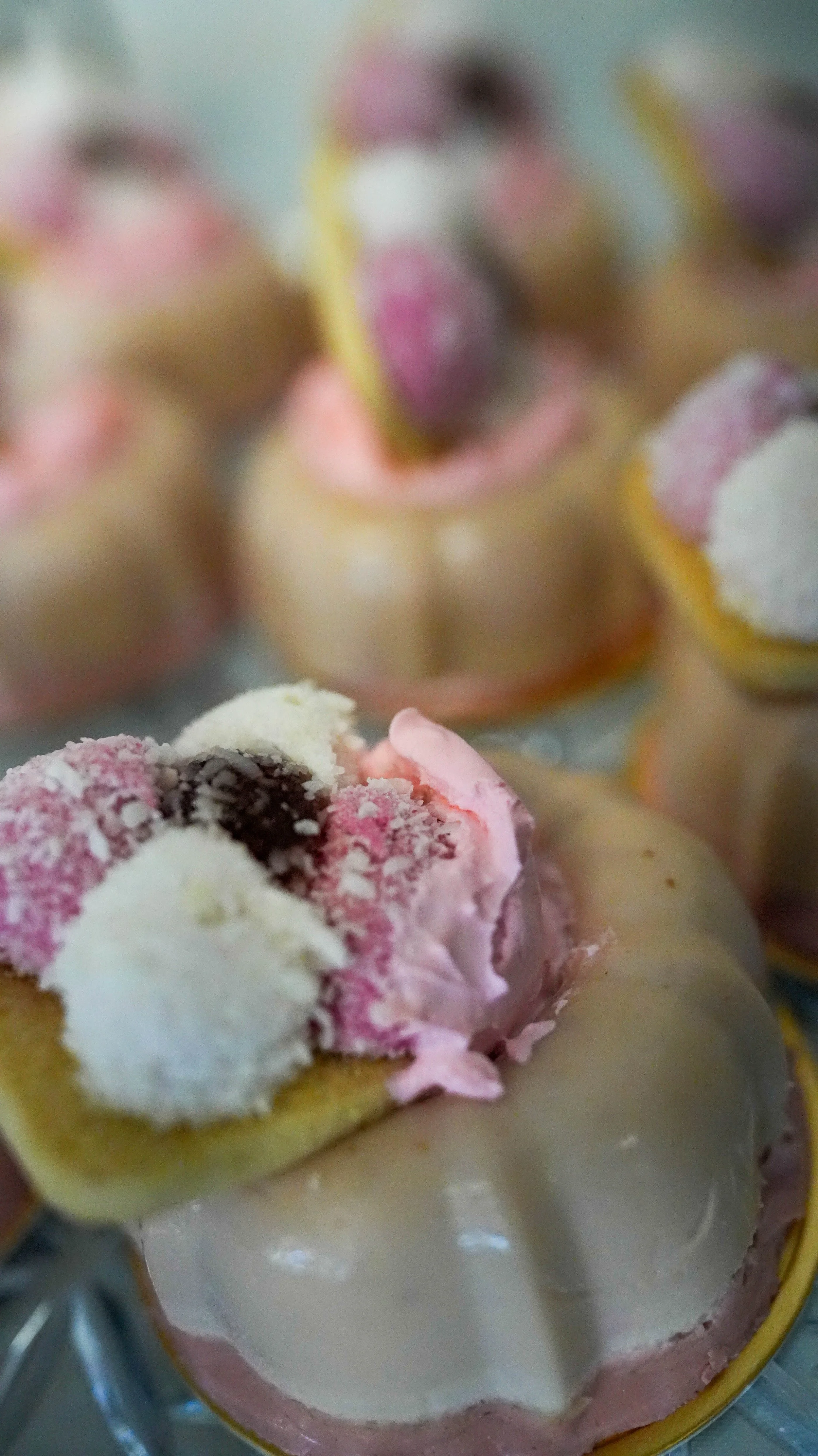 Close-up of a decorated cake featuring pink, white, and black frosting with small decorative elements.
