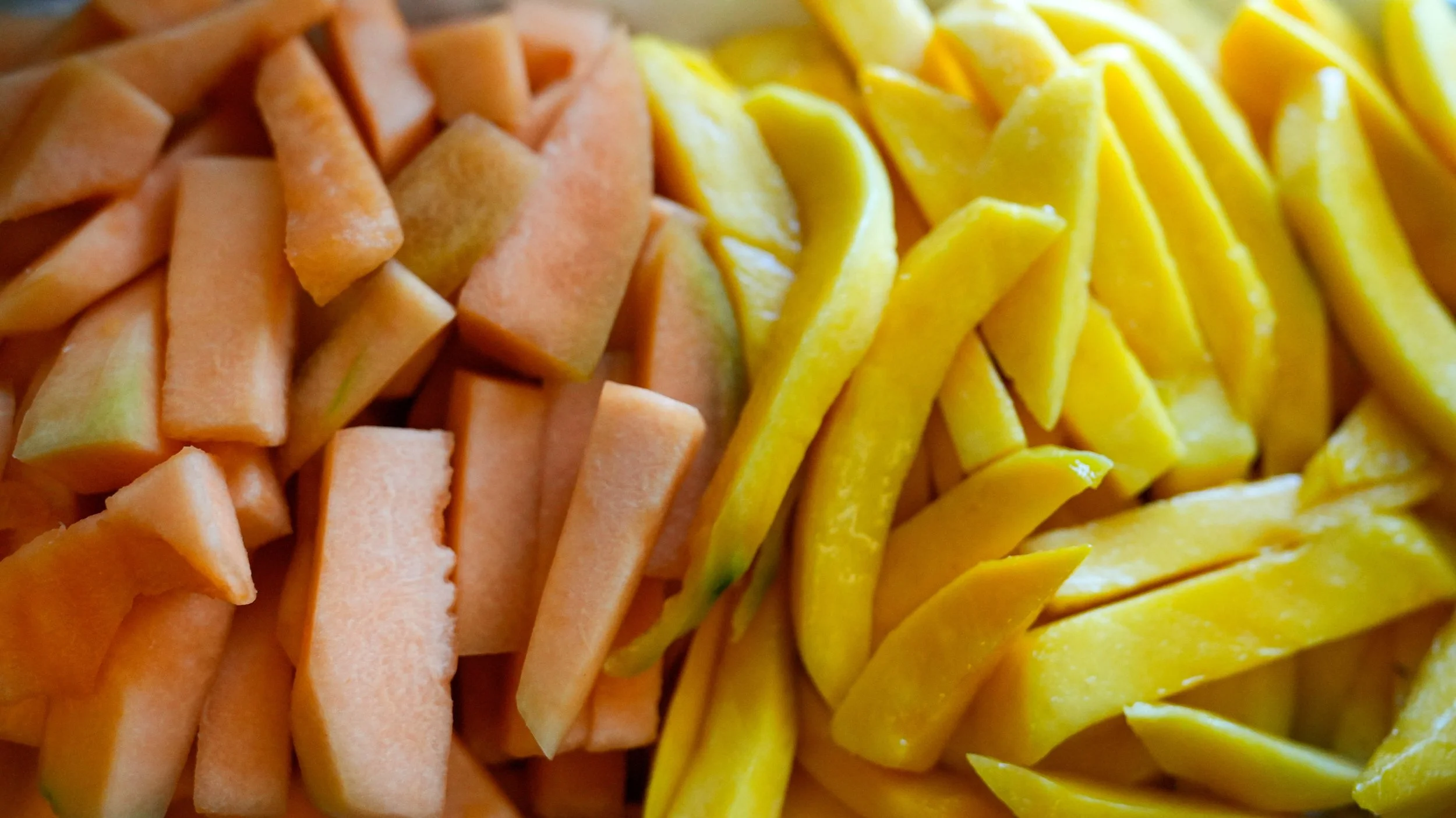 Close-up of sliced papaya and mango, arranged in a circular pattern.