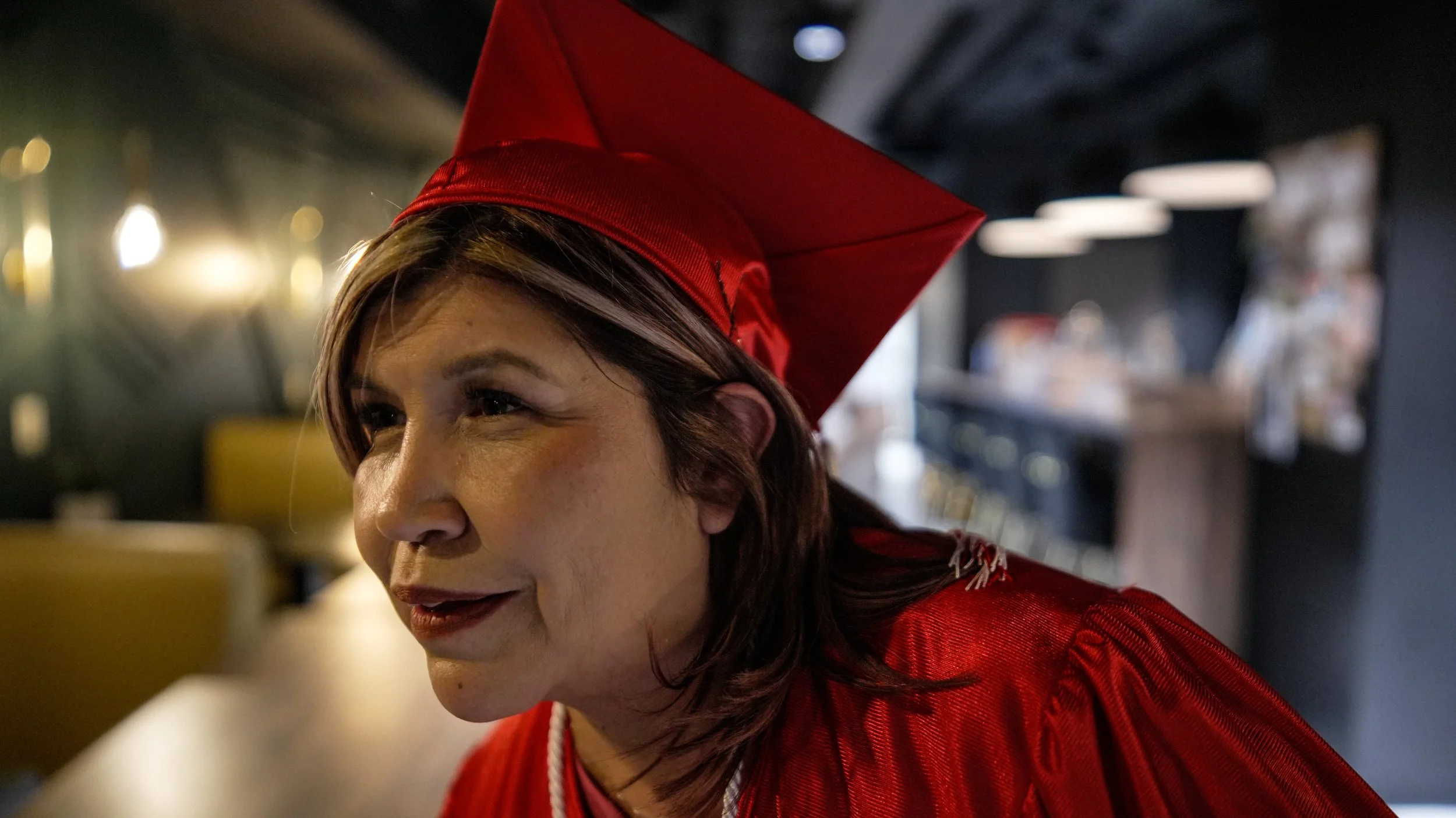 A woman in a red cap and red outfit inside a dimly lit space, possibly a restaurant or cafe.