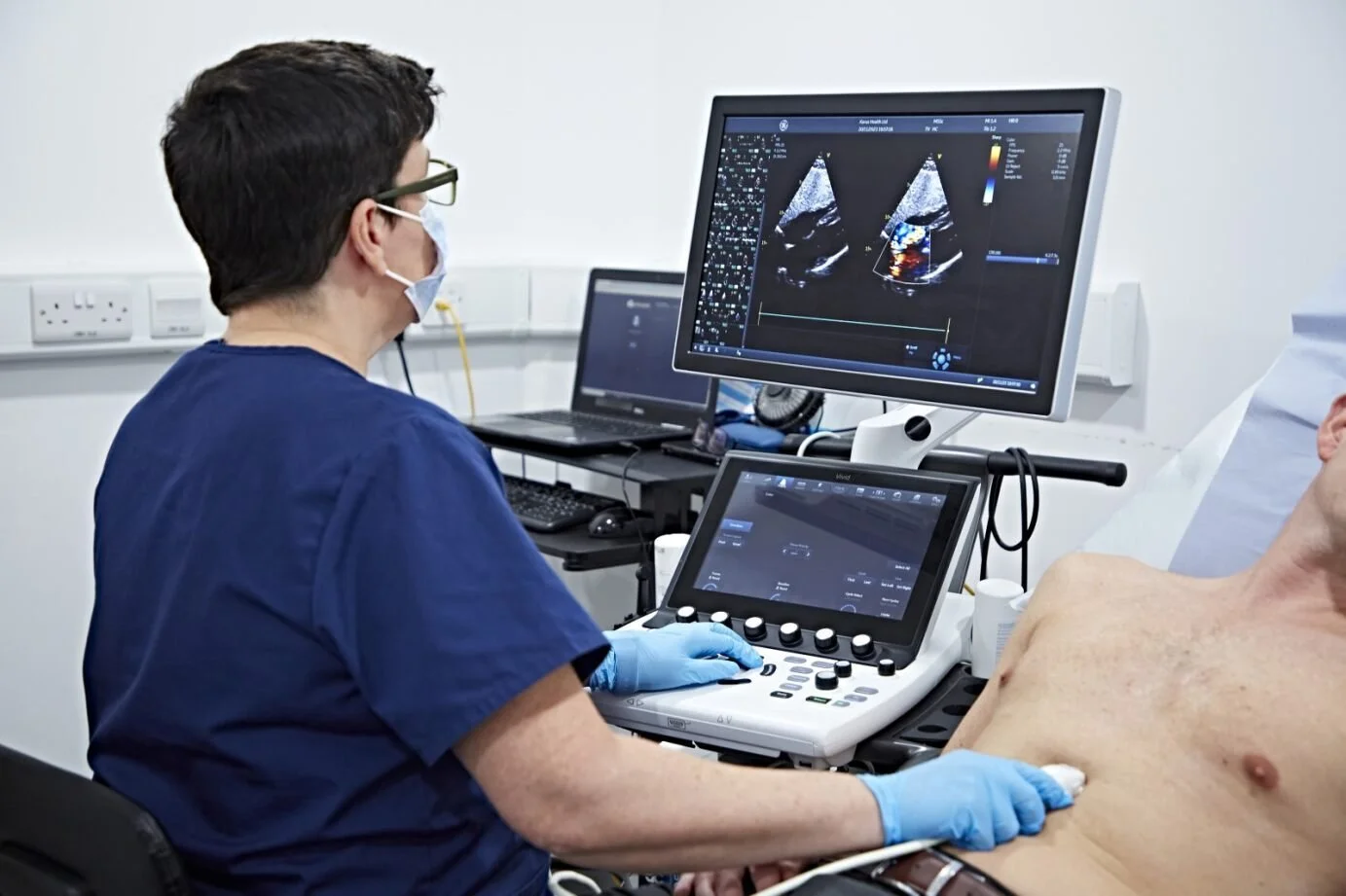 Medical professional performing an ultrasound on a patient in a clinical setting.