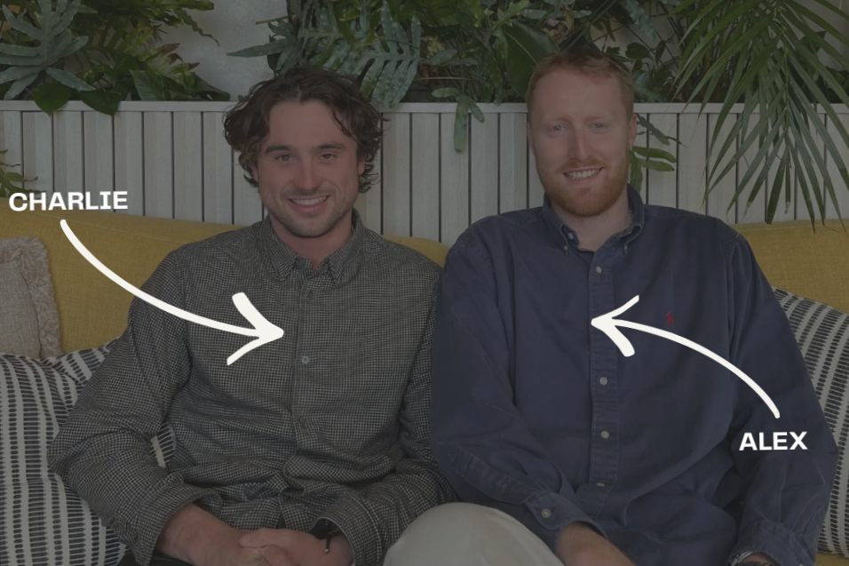 Two men sitting on a yellow sofa with plants and a white fence behind them. The man on the left, Charlie, has wavy brown hair and a checked shirt. The man on the right, Alex, has red hair, a beard, and is wearing a dark blue button-up shirt. Labels with arrows identify Charlie and Alex.