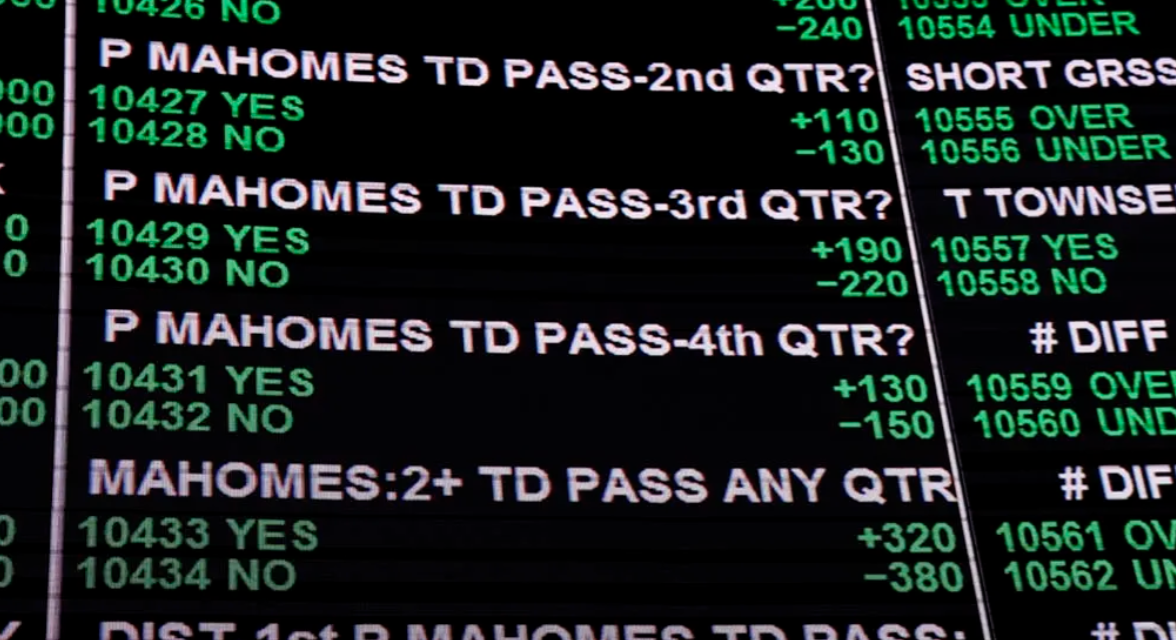 Close-up of a digital sports betting or lottery machine displaying numbers, choices, and indicators related to a football game, including results for passes and touchdowns by player 'Mahomes', with options marked YES and NO and corresponding numbers.
