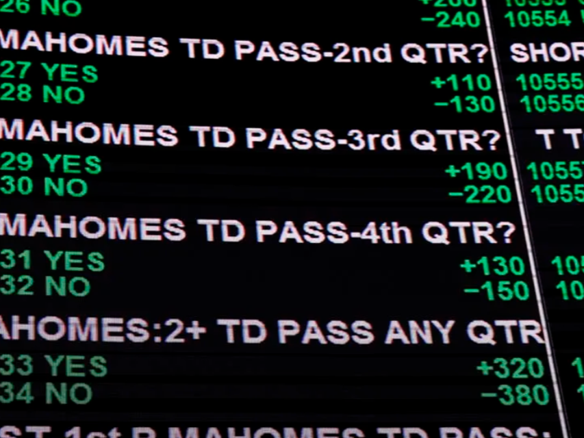 Close-up of a sports betting odds board displaying questions about DeVante Parker's pass completions for various quarters, with odds and betting options in green and red text.