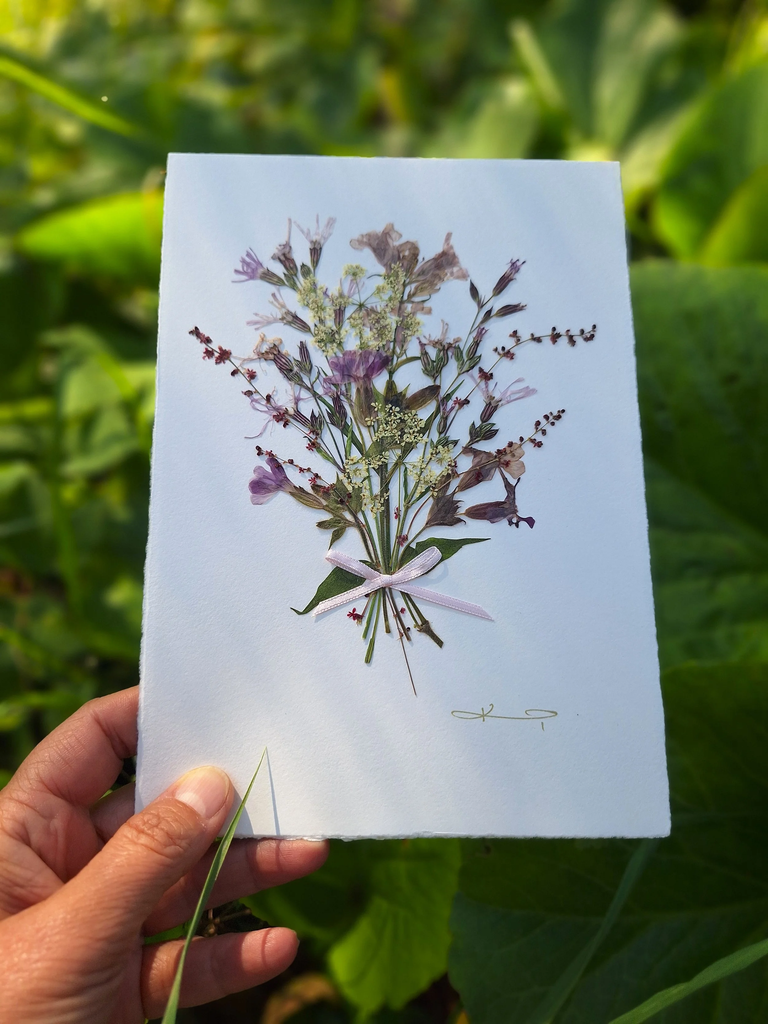 A beautiful, artisan greeting card featuring a bouquet of authentic pressed flowers in purple colours, carefully hand-sourced and crafted.