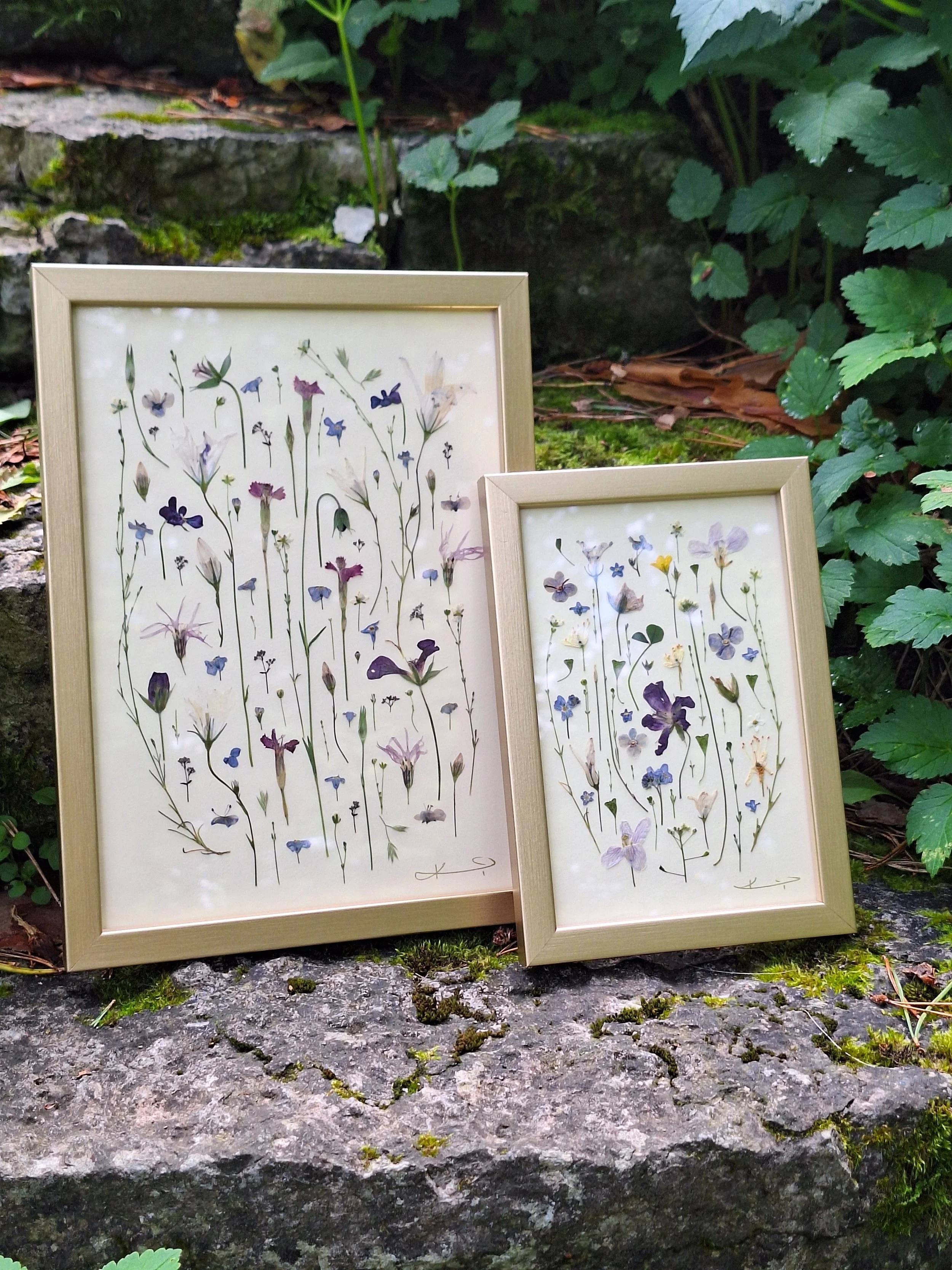 Vertical botanical composition of real pressed wildflower stems in purple and blue tones, showcased inside a sleek, polished metallic gold frame.