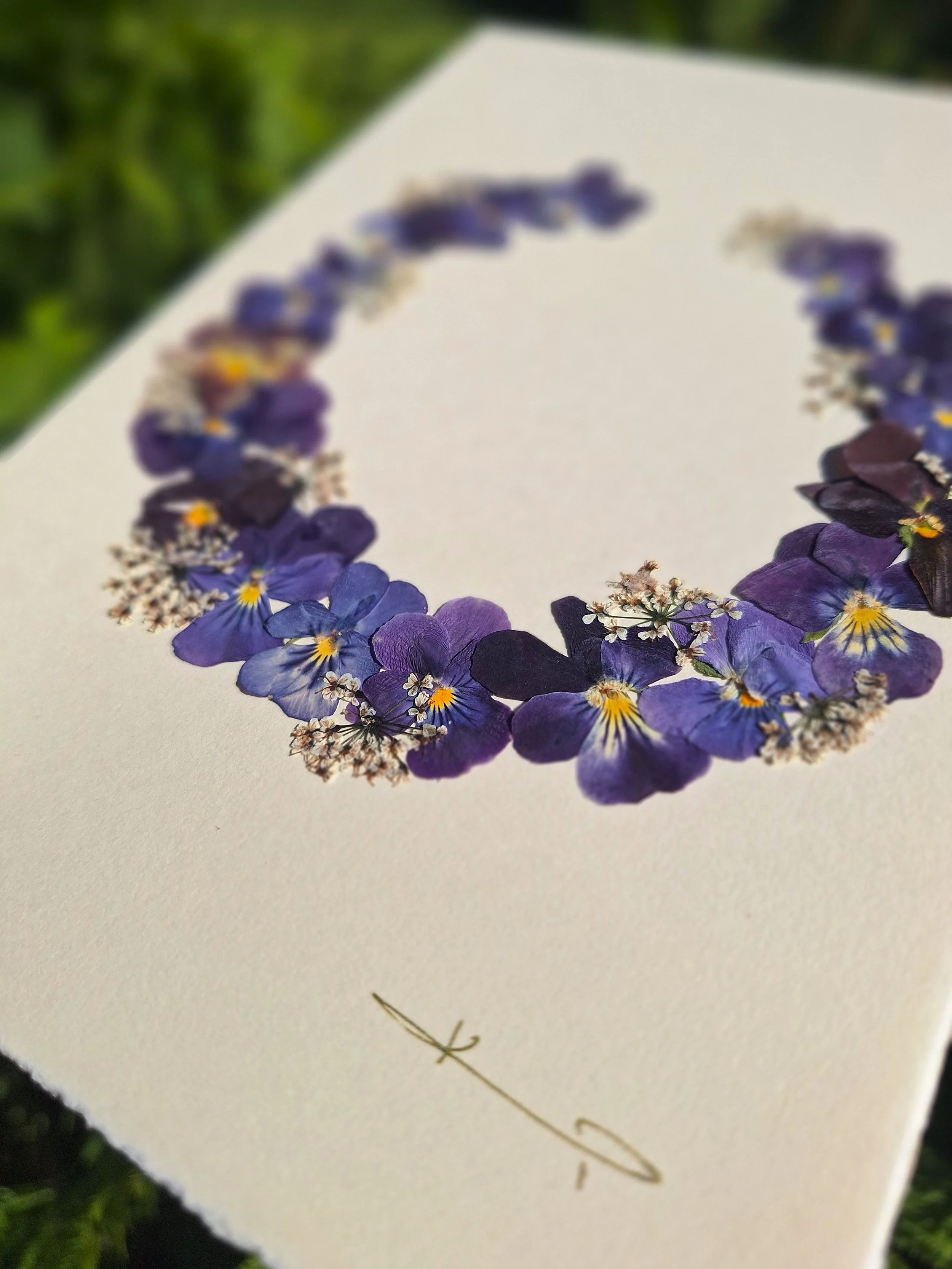It is a unique greeting card featuring a dark purple wreath made of real pressed pansies. A gift for your loved ones or a sweet addition to your home decor.