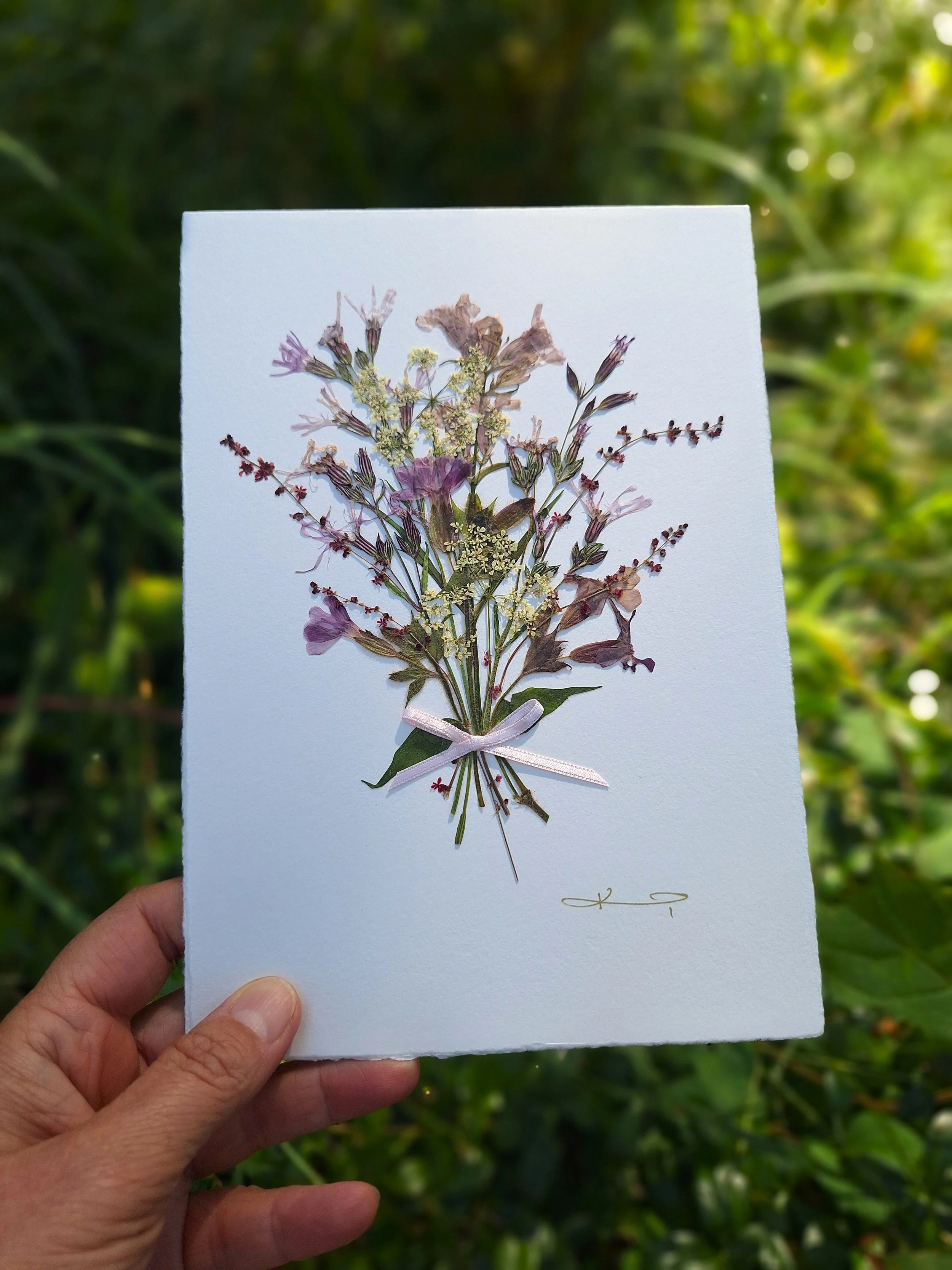 A beautiful, artisan greeting card featuring a bouquet of authentic pressed flowers in purple colours, carefully hand-sourced and crafted.