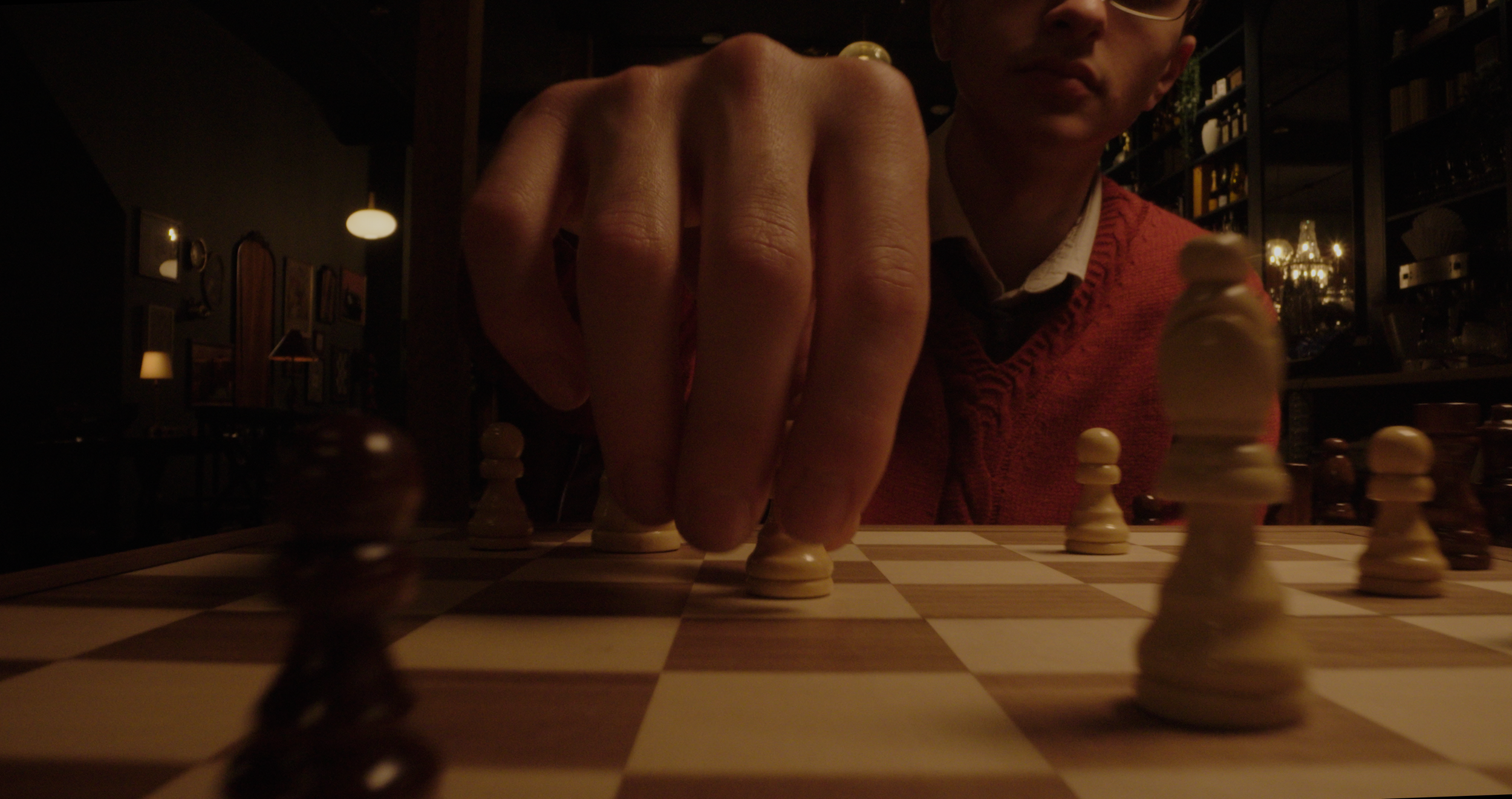 dolly probe lens shot of man playing chess setting down a piece in dark cinematic lighting