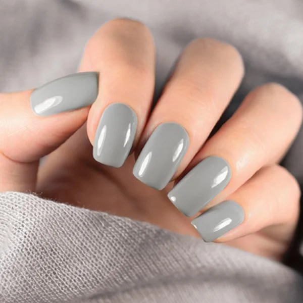 Close-up of a hand showing five fingernails painted with glossy light gray nail polish.