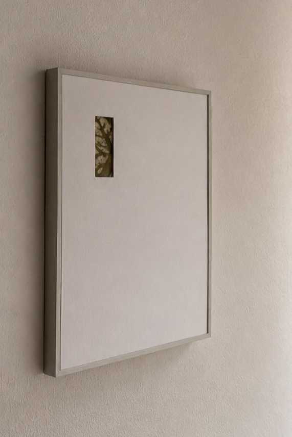 Empty white framed box with a small viewing window, mounted on a beige wall.