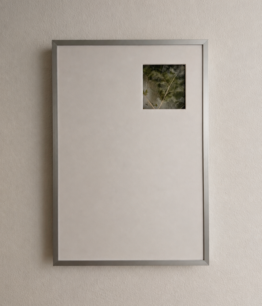 Framed wall art with a small window showing green foliage, mounted on a light-colored textured wall.