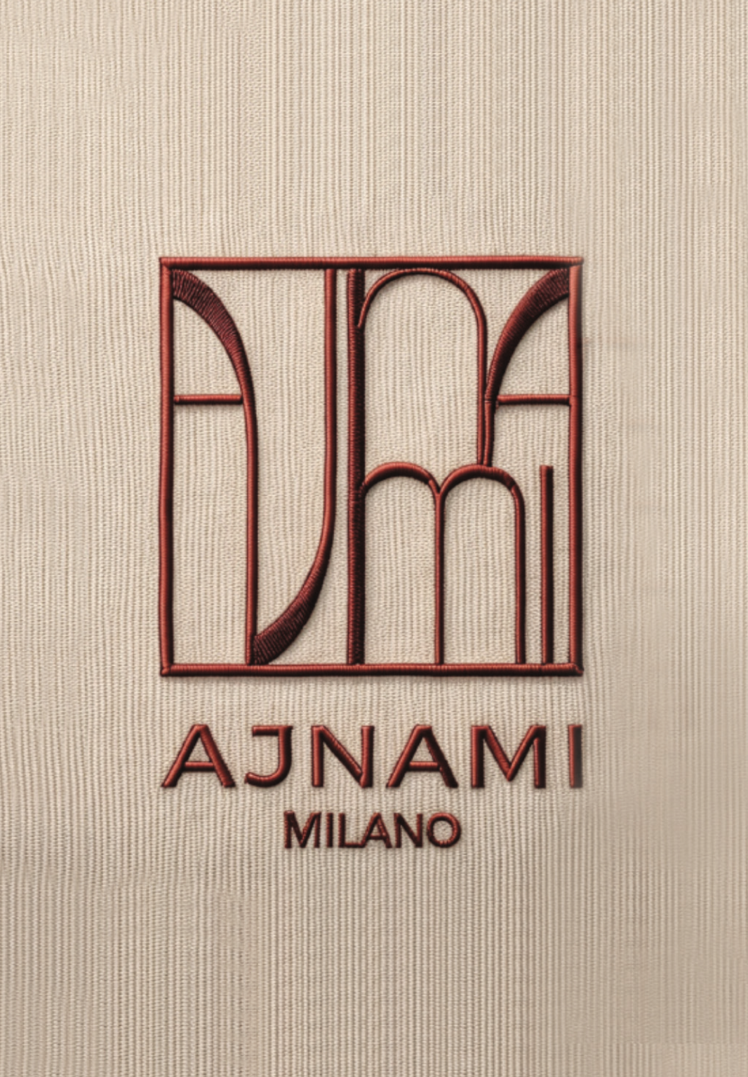 Embroidery featuring the designer logo 'A' and 'M' with the words 'AJNAMM MILANO' on beige fabric.
