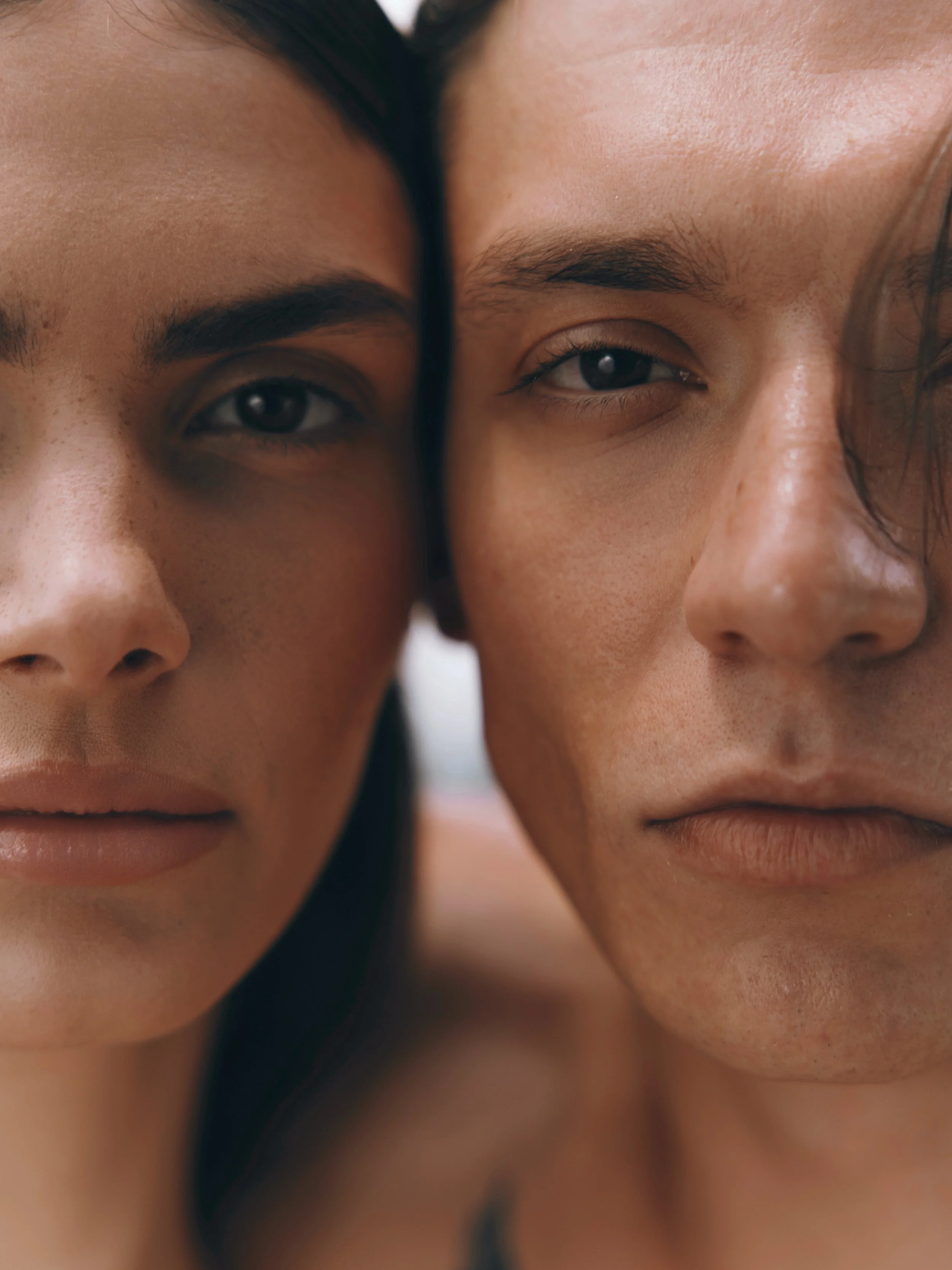 Close-up of two people's faces pressed together, showing their eyes, eyebrows, and parts of their noses and mouths.