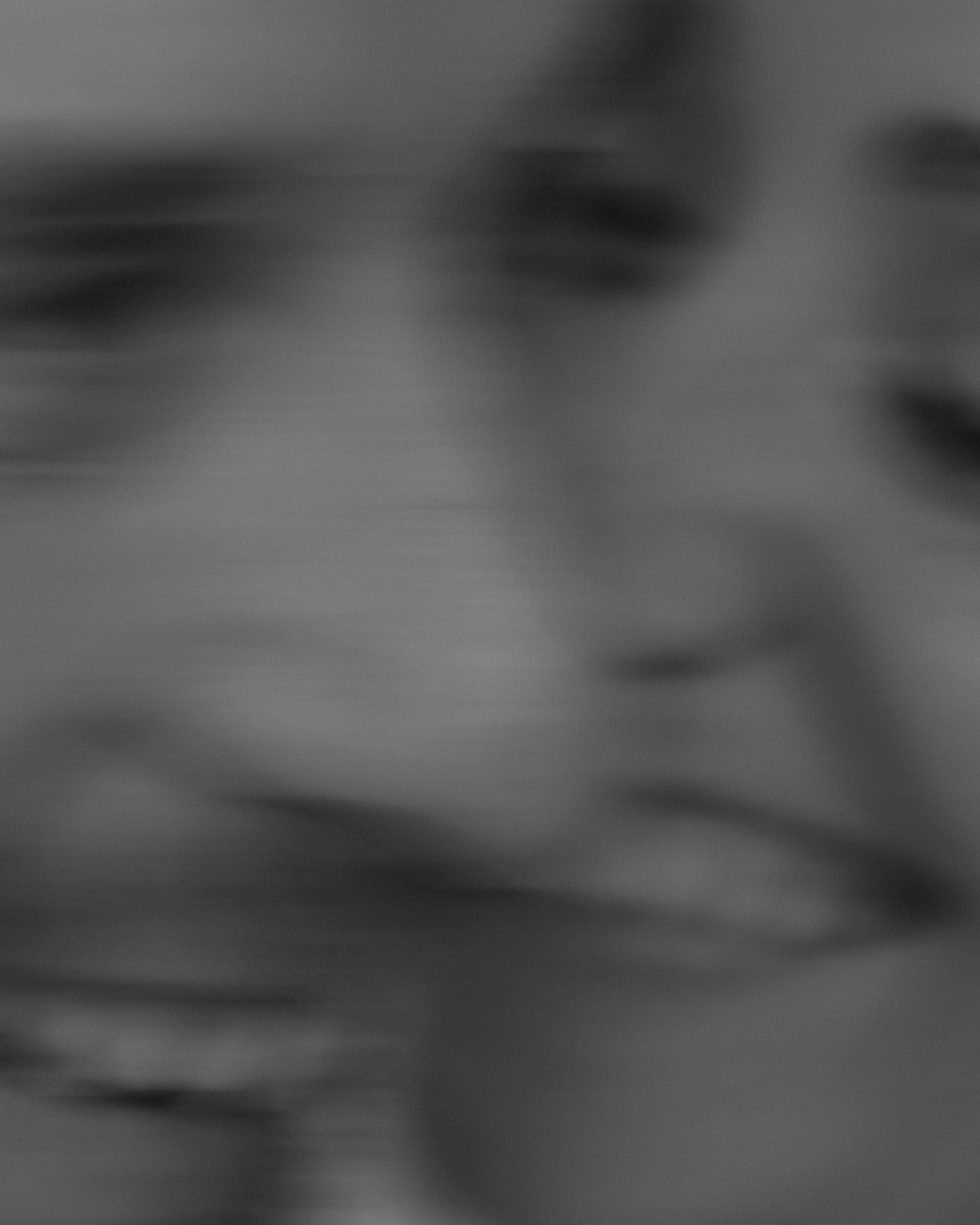 The image is a black and white photograph of a person holding a camera to their face, capturing a photo.