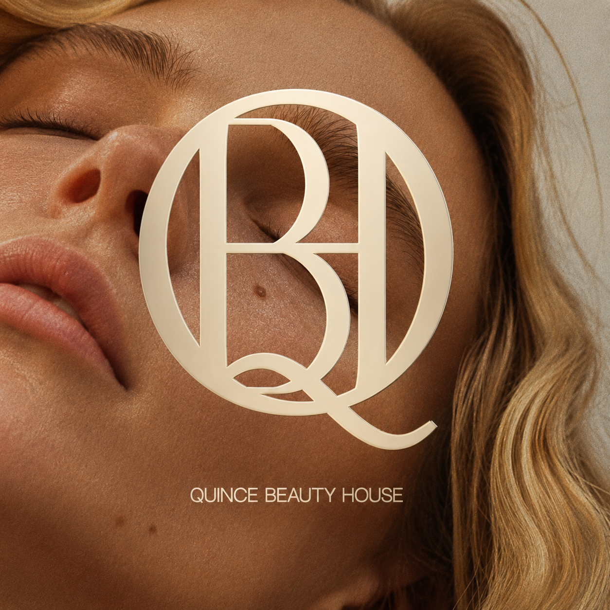 Close-up of a woman's face with a neutral expression, featuring natural makeup, wavy hair, and a large Quince Beauty House logo overlaying the image.