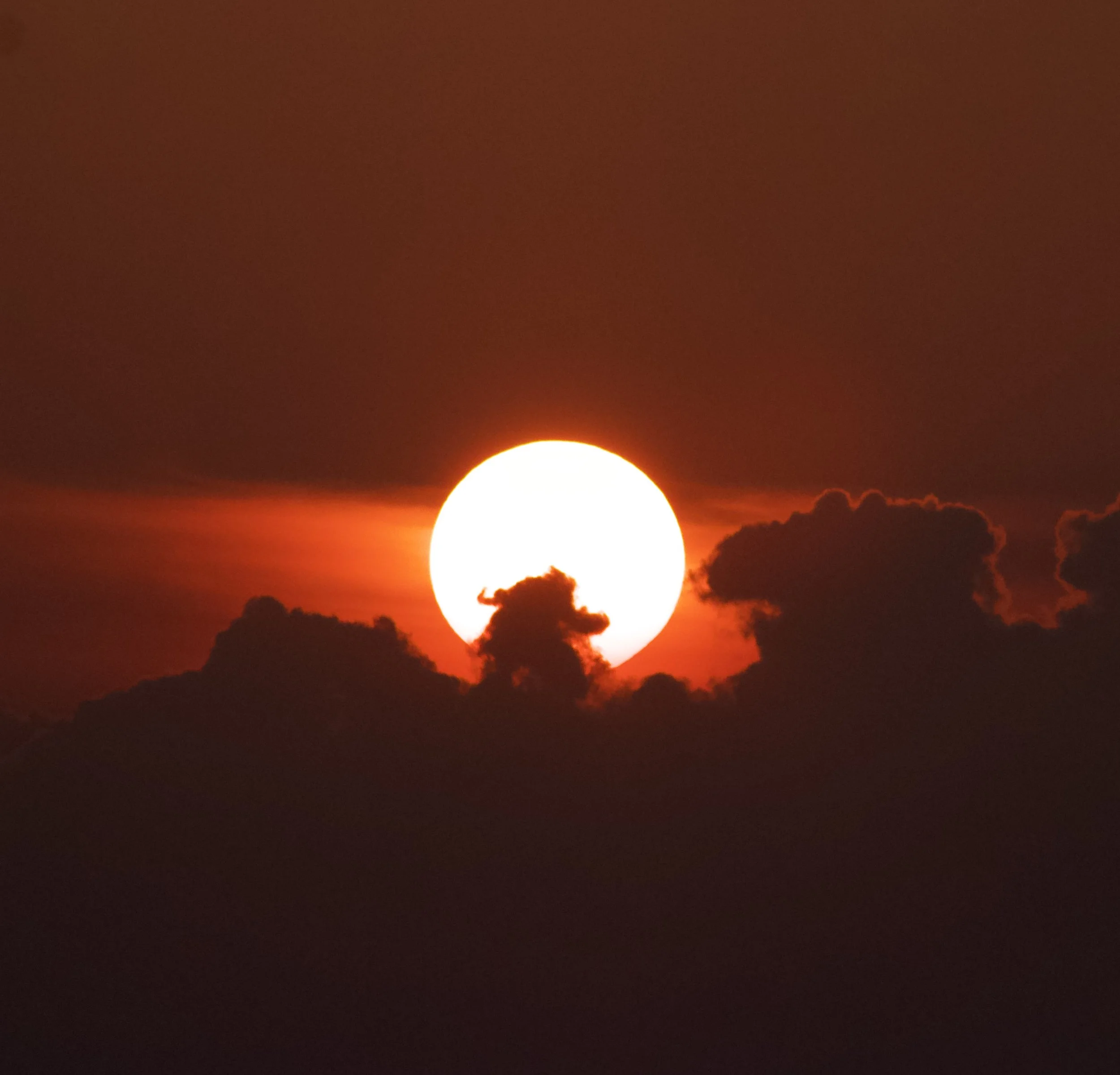 Sunset with the sun partially obscured by clouds, creating an orange glow in the sky, From the Sunset cruise, Guraidhoo Maldives.