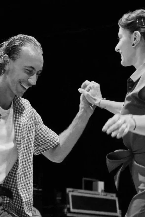 Deux femmes souriantes s'engageant dans une poignée de main ou une poignée de bras dans une ambiance amicale.