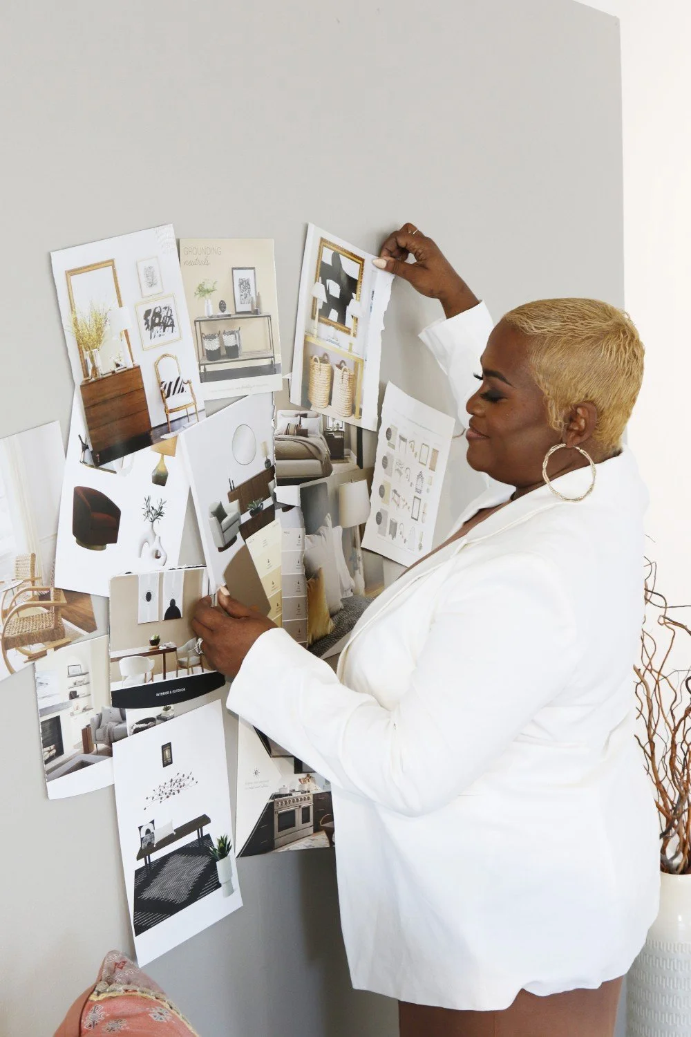 Woman in a white blazer looks at interior design mood board with furniture and decor images