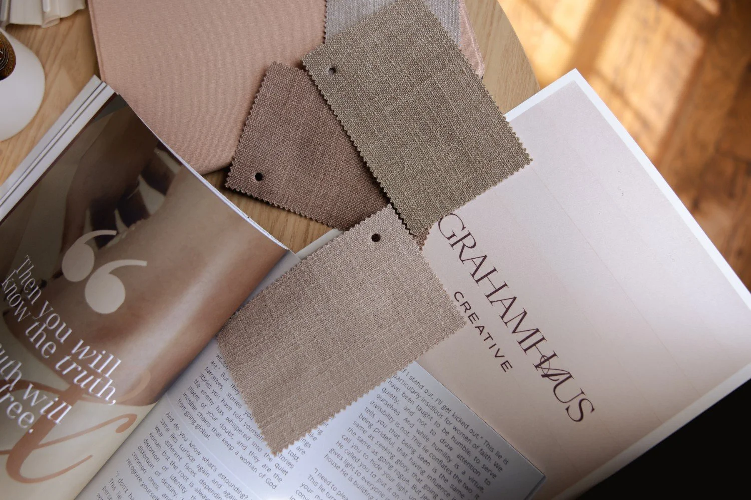 Fabric swatches, a magazine, and a booklet on a wooden surface.