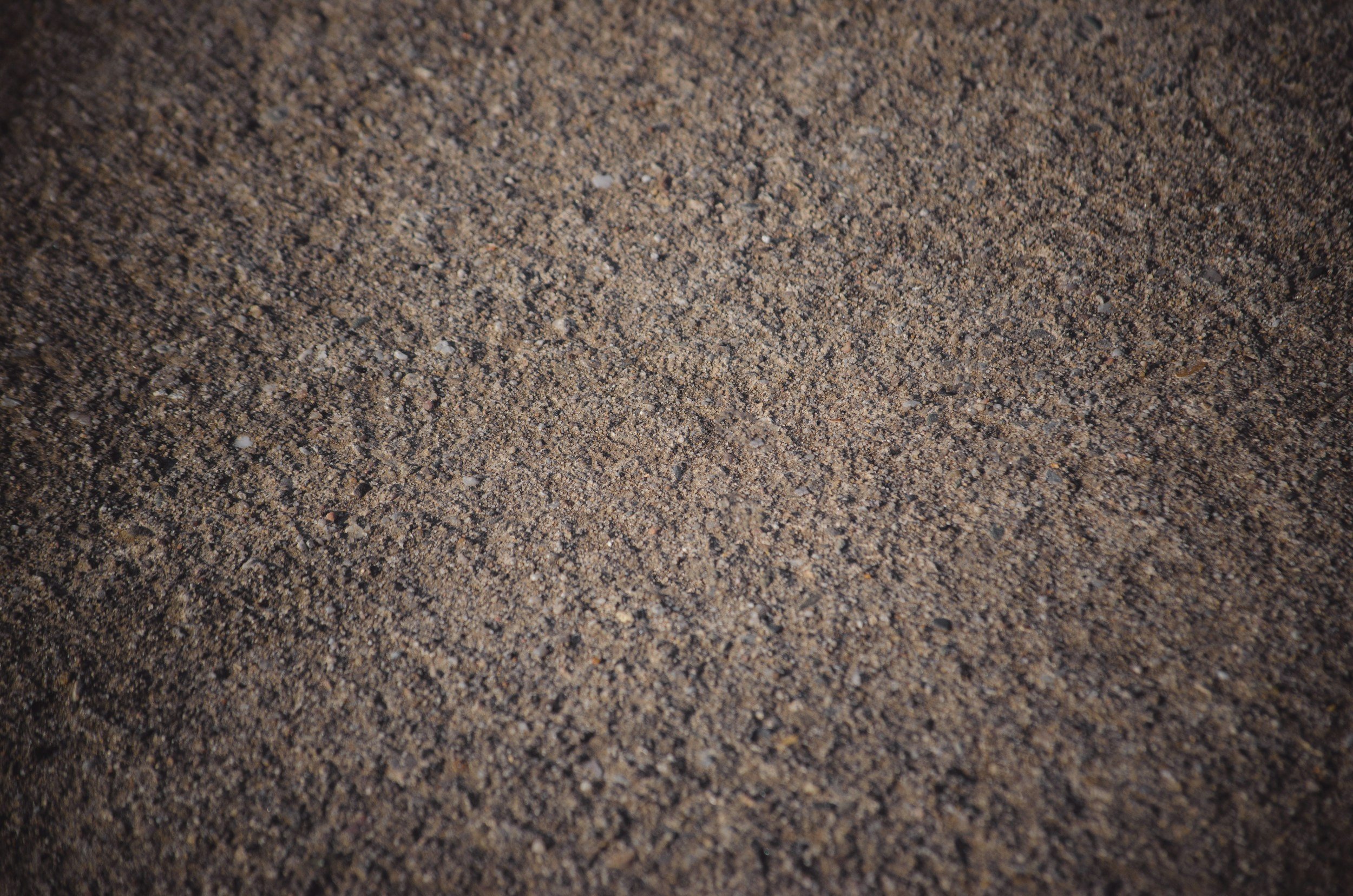 Close-up image of a sandy surface with small grains of various colors.