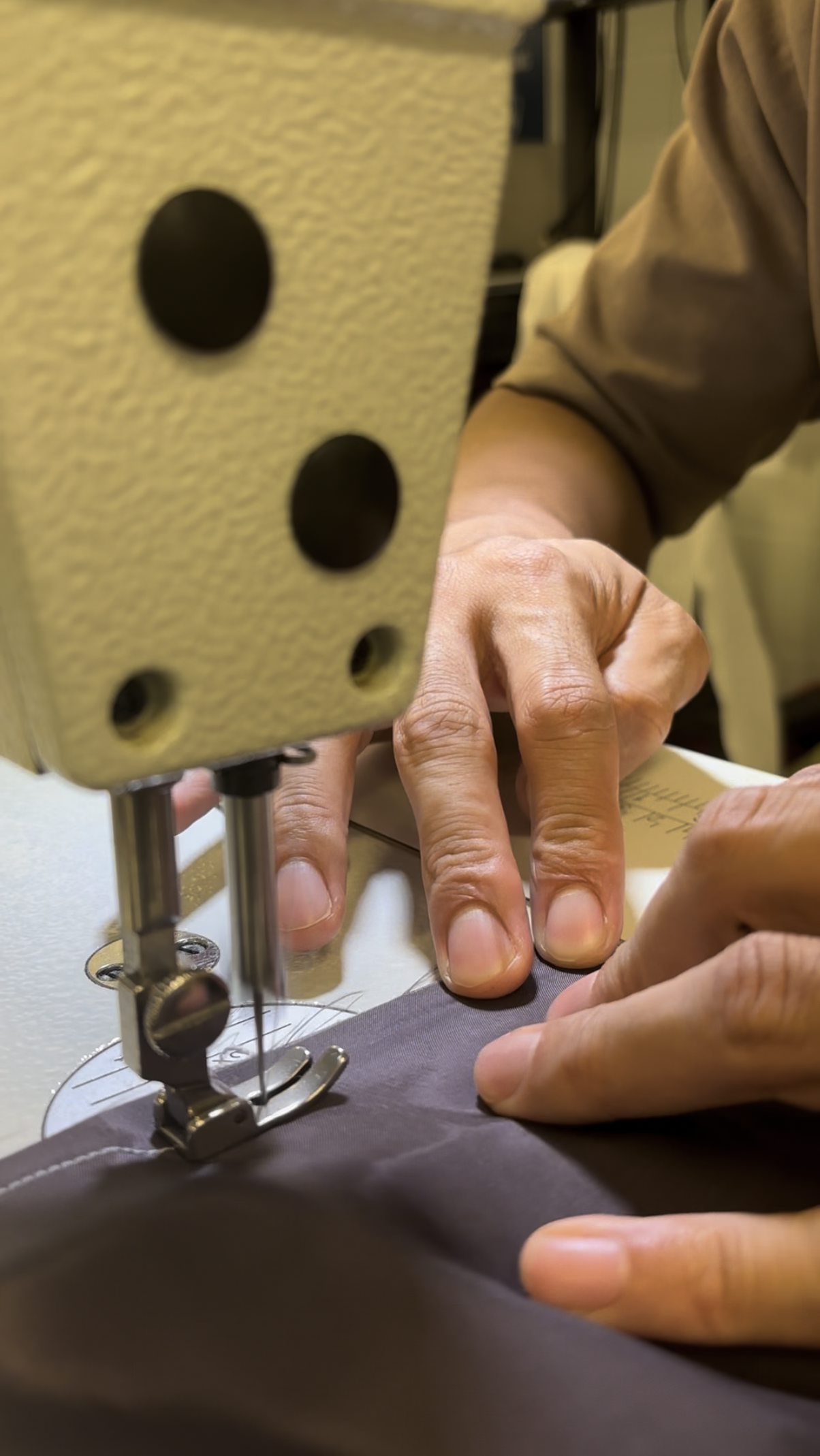 Carlos sewing a pocket with an industrial sewing machine, his hands guiding the material.