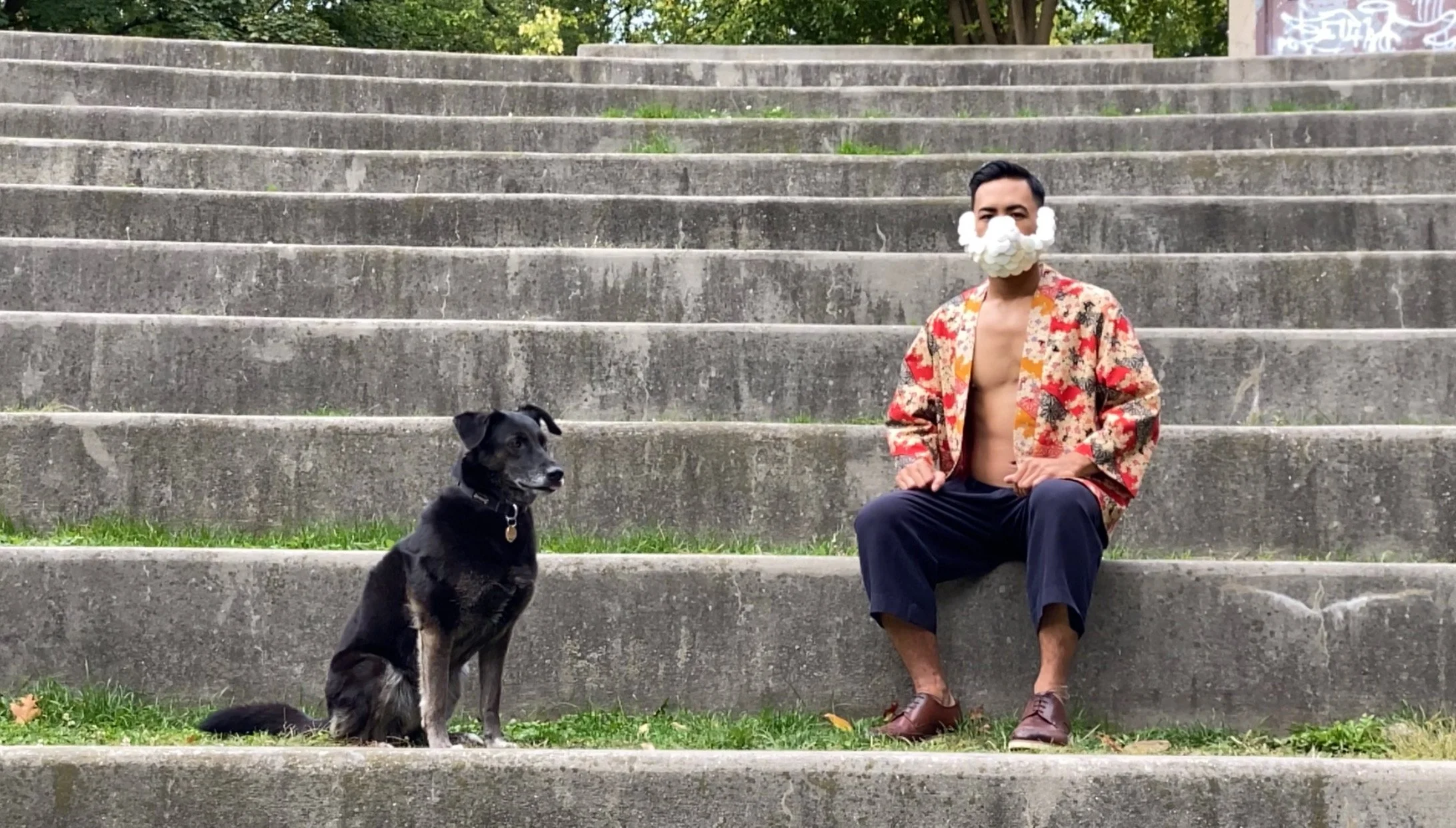 Carlos wearing his original designs, sitting beside his dog Lilly.
