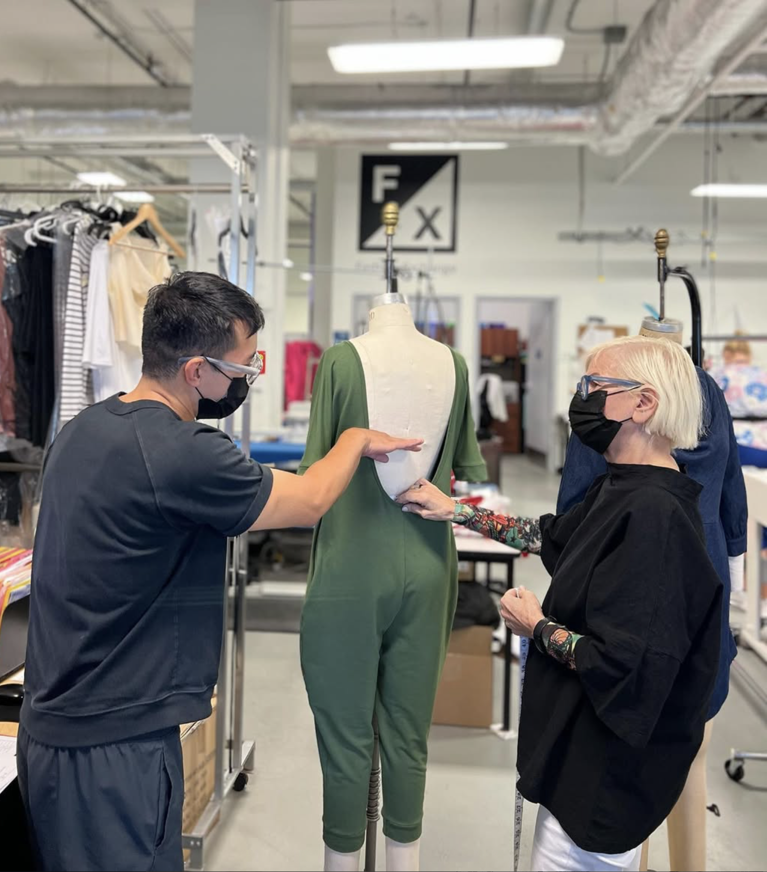 Carlos and his production manager assessing the fit of a jumpsuit sample on a mannequin.