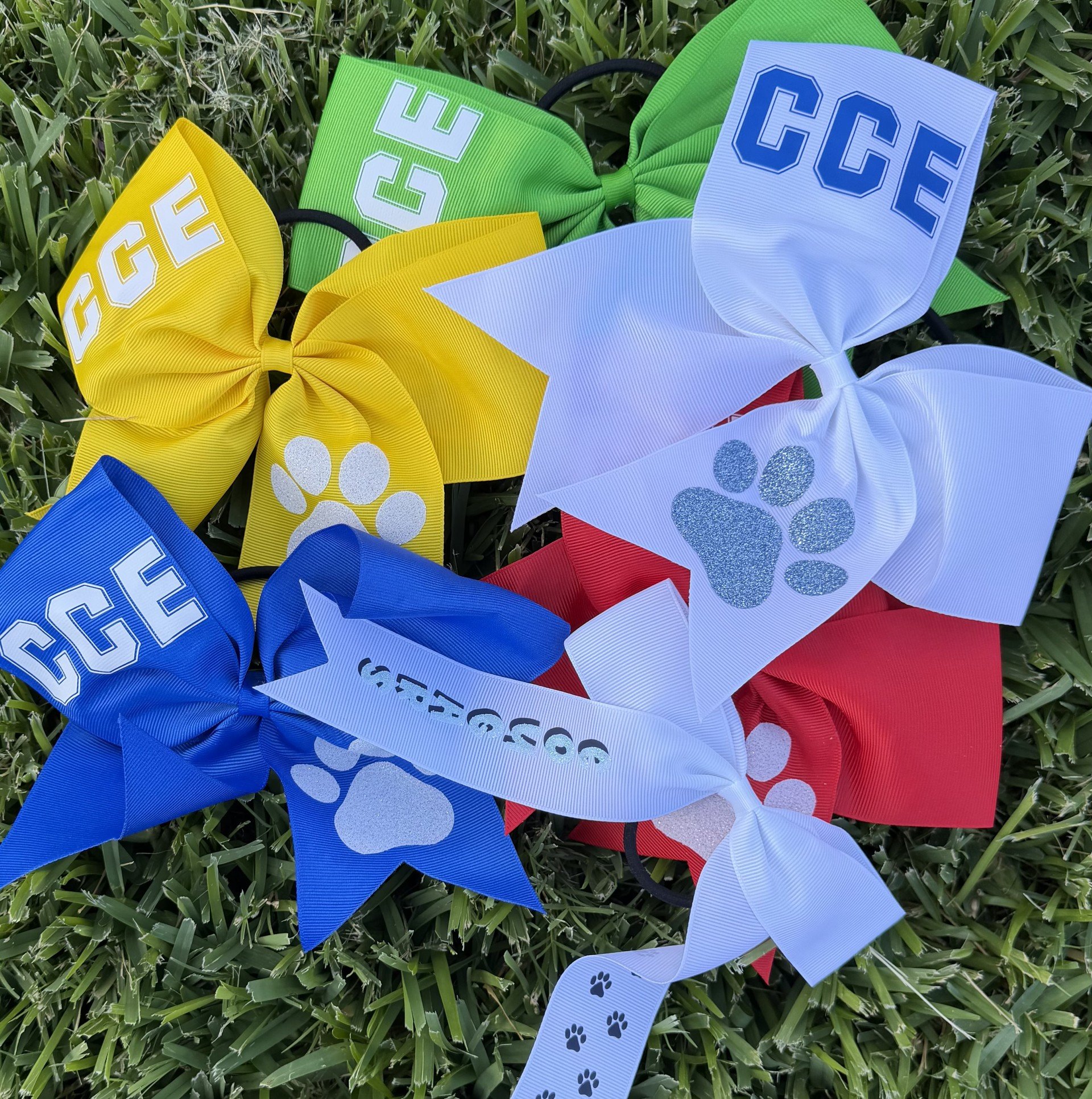 Colorful bow ties arranged on grass, featuring the names of dog breeds like Beagle and Cocker Spaniel with paw print designs.