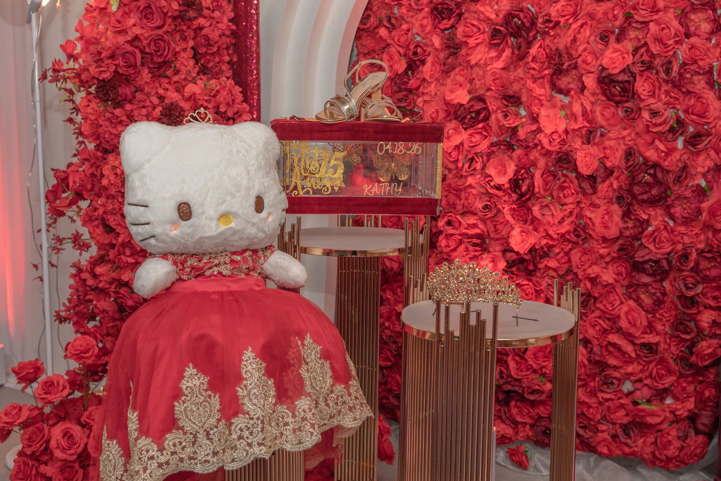 A hello kitty plushie with a quince dress and tiara.