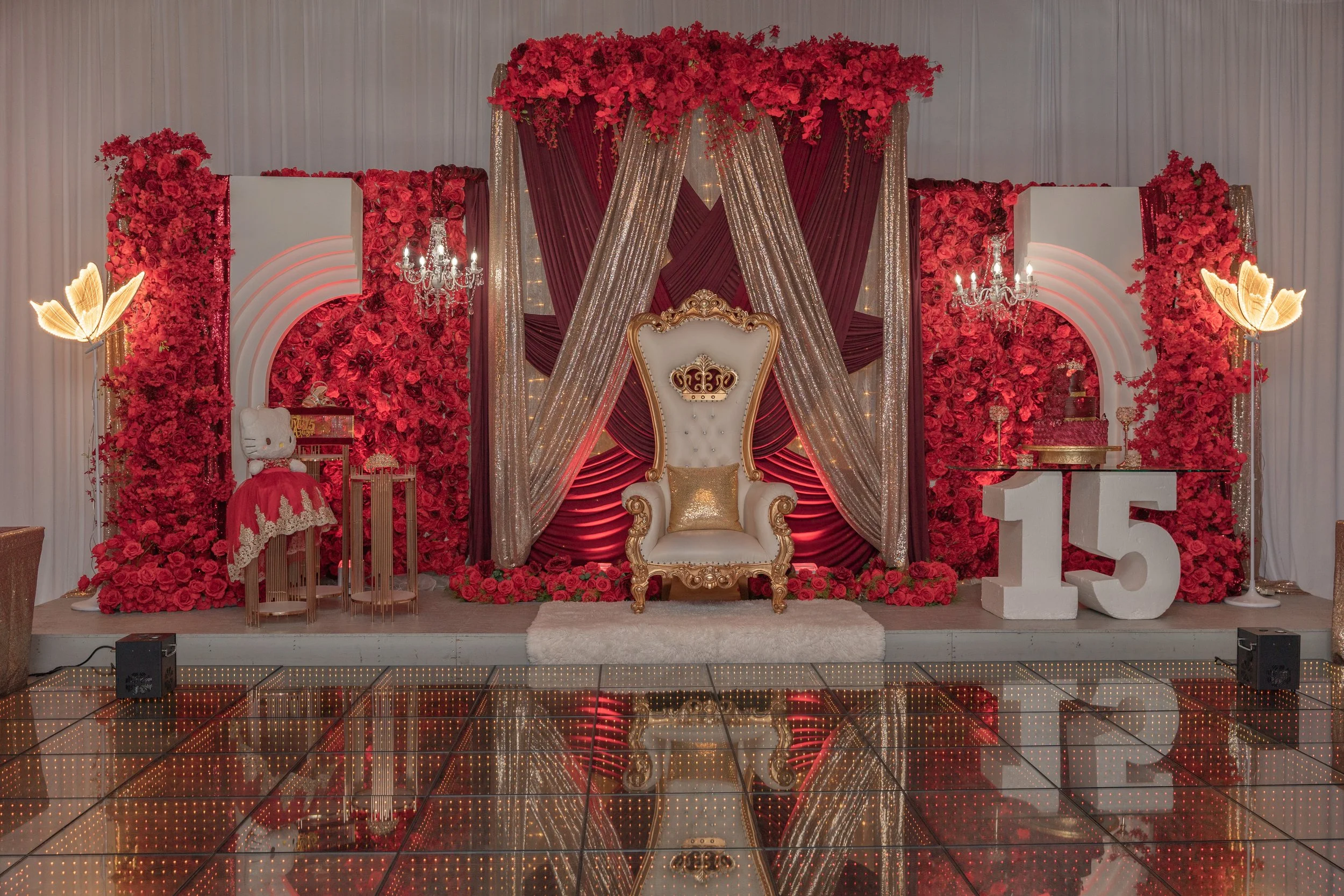 A red themed quince image of the queen chair, hello kitty stuffy, and letters 15.