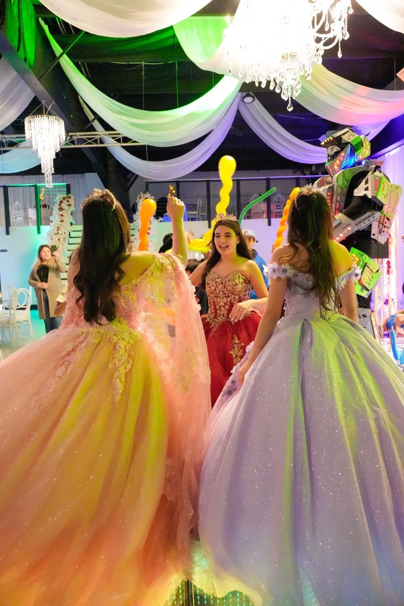 Three girls dancing on the dance floor in ball dresses.