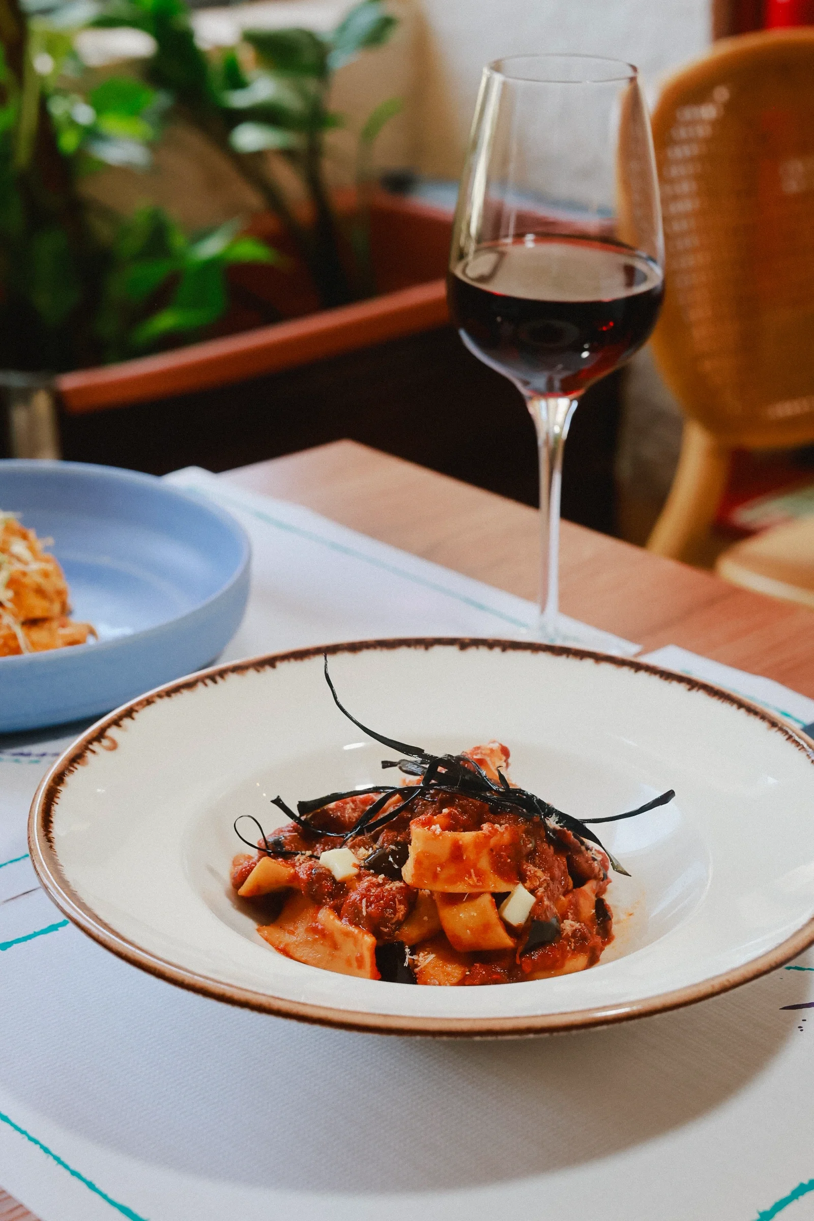 A bowl of pappardelle alla Norma served with Italian red wine at VERA's terrace-side tables in Porto.