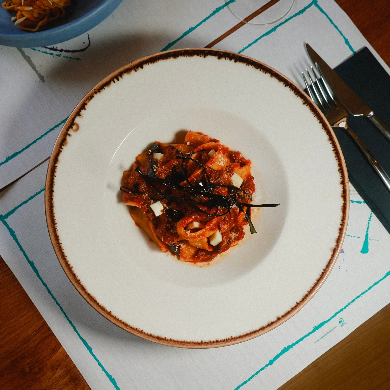 Pappardelle alla Norma from above: wide handmade ribbons with aubergine, tomato sauce, smoked cheese and fried basil.
