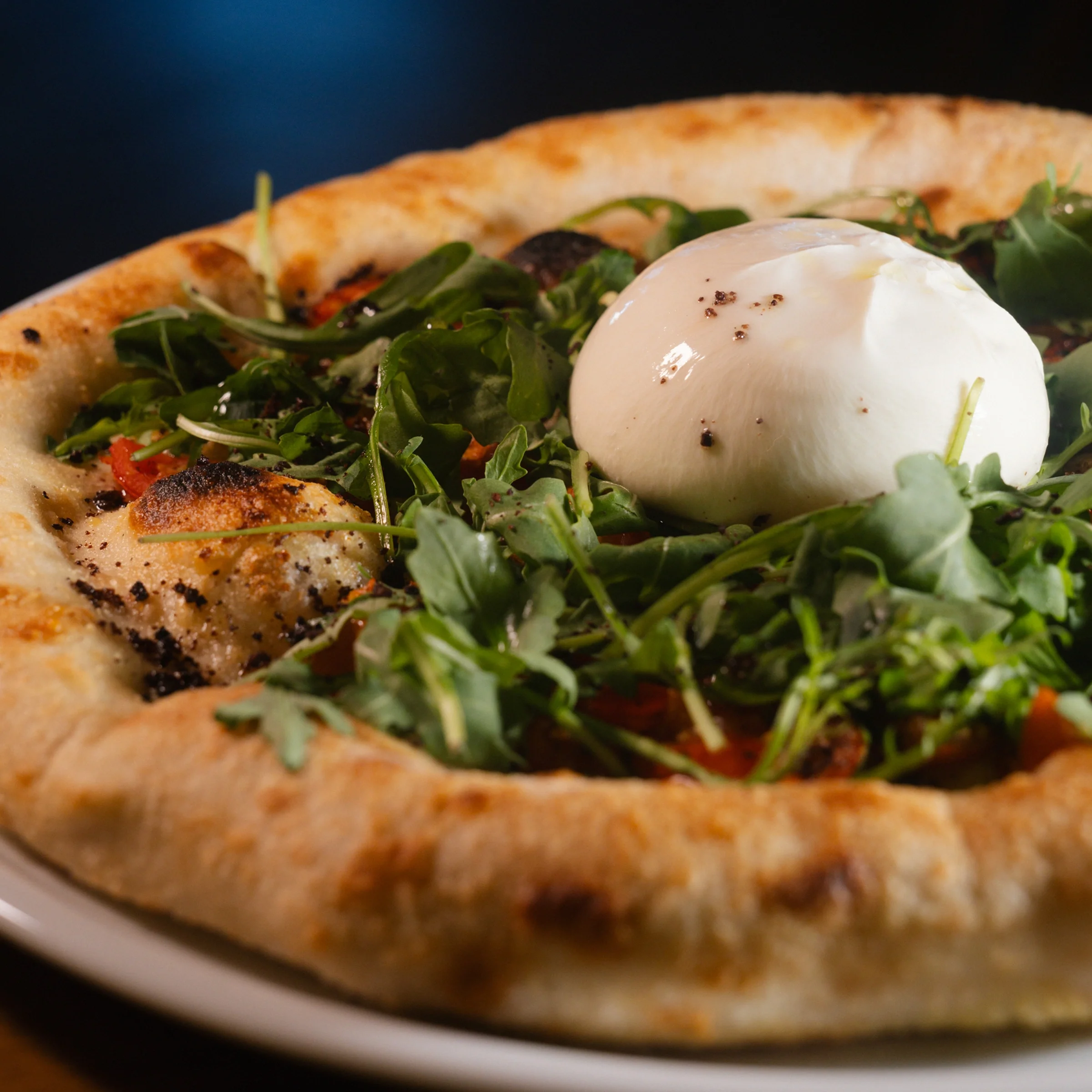 Pizza Filetto at VERA in Porto: Neapolitan base with fresh cherry tomato, whole burrata, rocket and black olive dust on a puffed leopard-spotted cornicione.