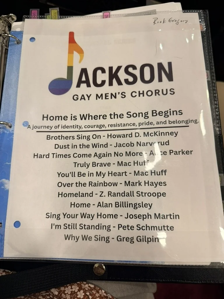 Song list for Jackson Gay Men's Chorus, including titles and composers, under a rainbow-colored musical note logo.