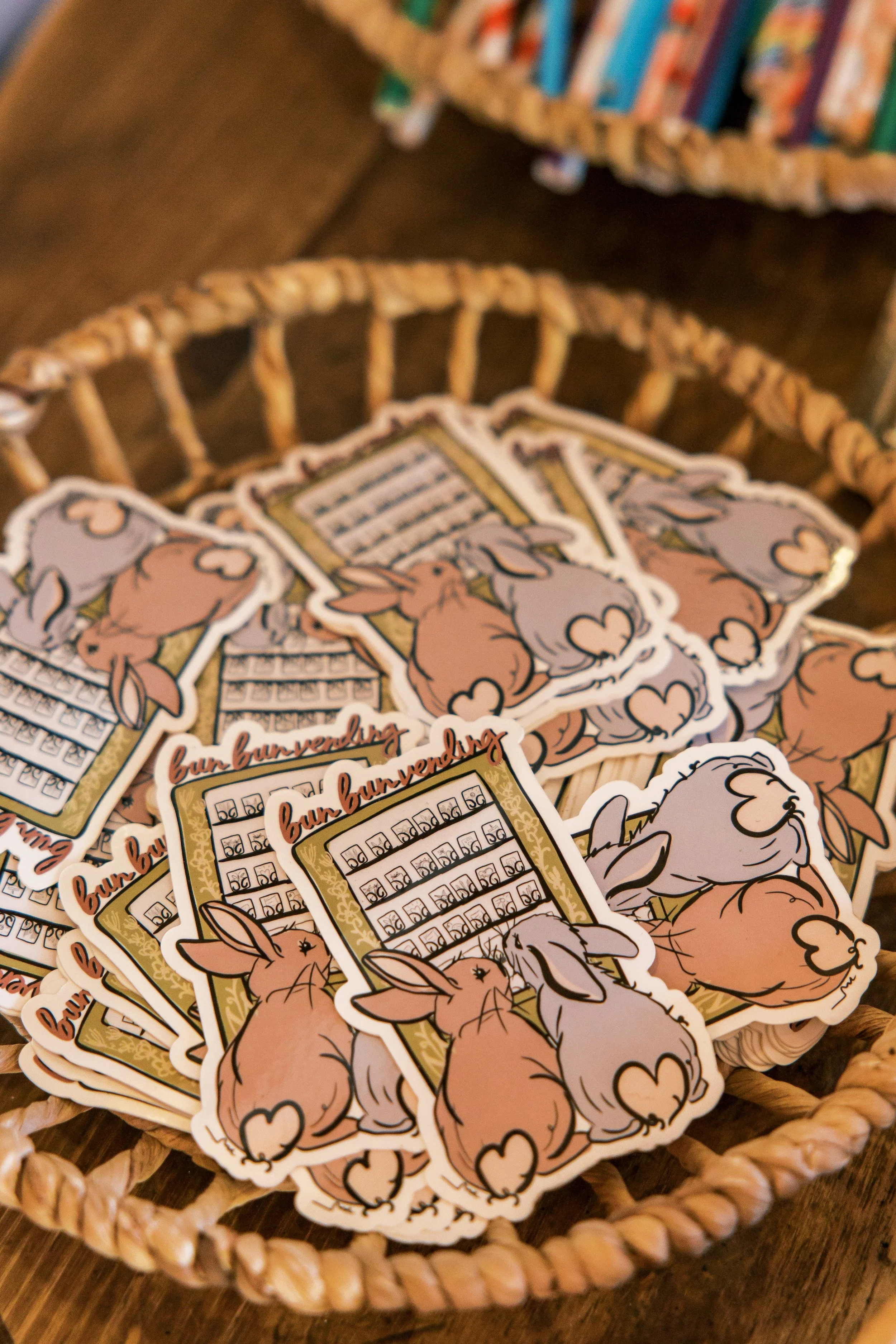 A woven basket filled with bunny-shaped stickers. The stickers depict a brown bunny with a white tail and a small heart-shaped nose, along with a calendar-like grid and the words 'bun bunvending' written on them.