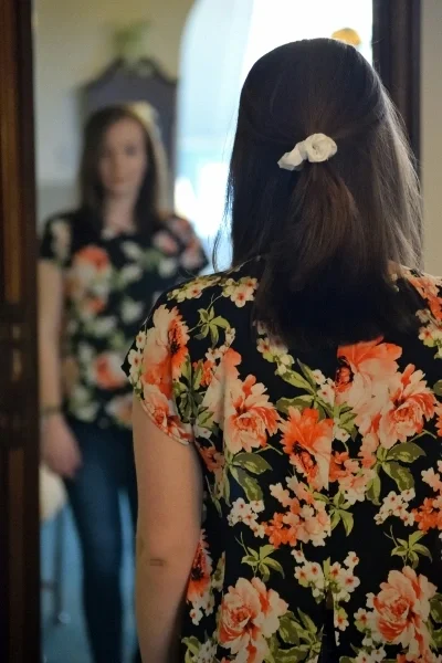 Woman standing in front of full length mirror looking at reflection