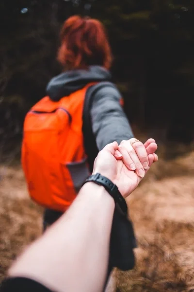One person leading another by holding hands