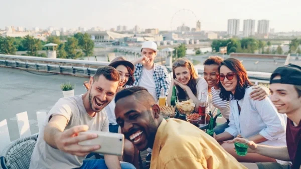 Group of young people at outdoor dining table posing for selfie