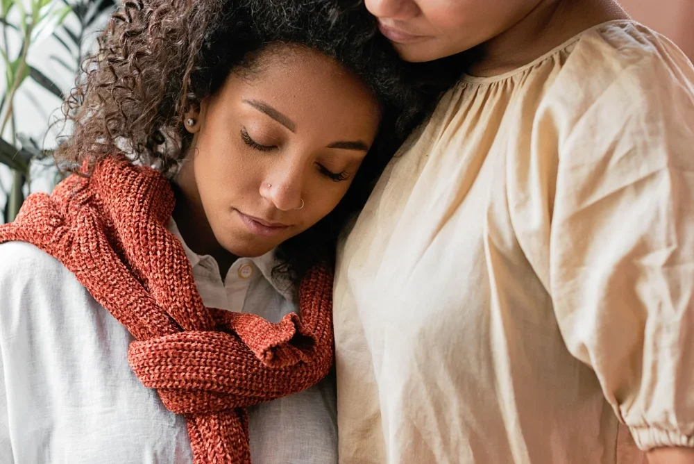 Woman resting her head against another woman's chest