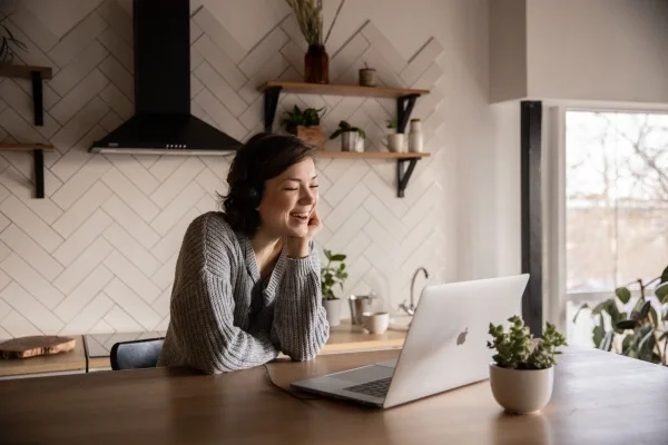 Woman sitting on video call in a kitchen smiling