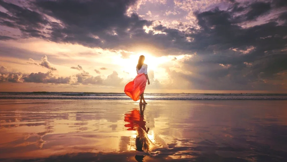 Woman in pink dress on the beach at sunset
