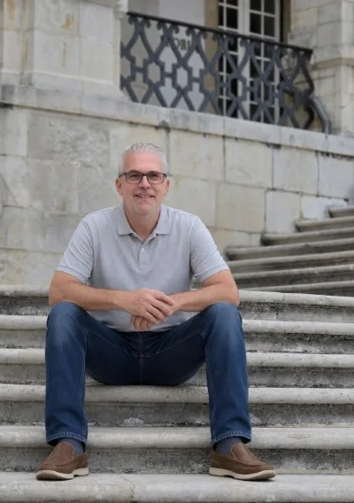 Tom Adams sitting on stairs with hands together